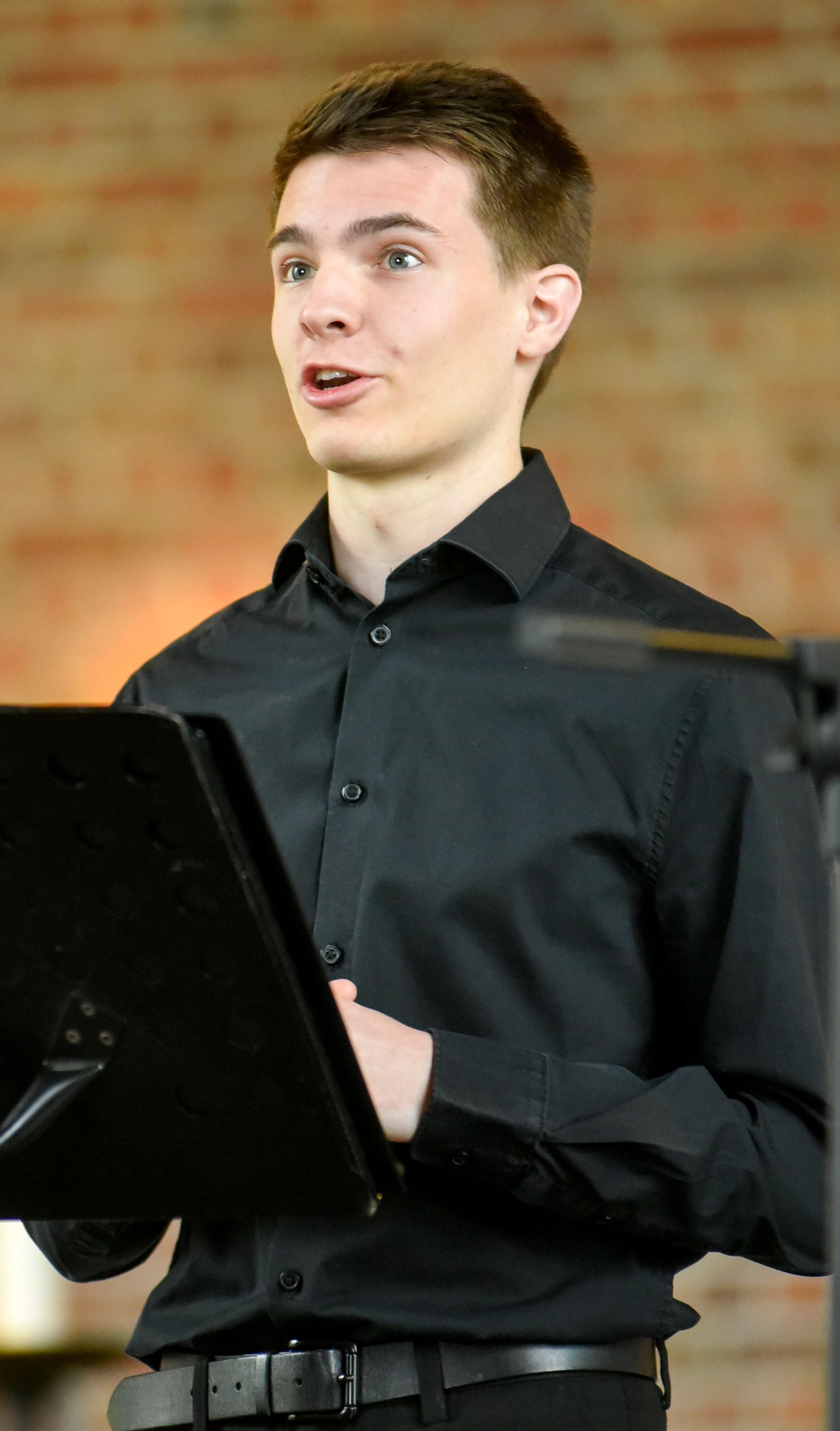 Auf dem Bild ist ein junger Mann zu sehen, der singt.