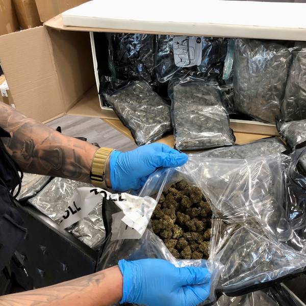 Ein Zollbeamter zeigt einen geöffneten Beutel mit Marihuana.