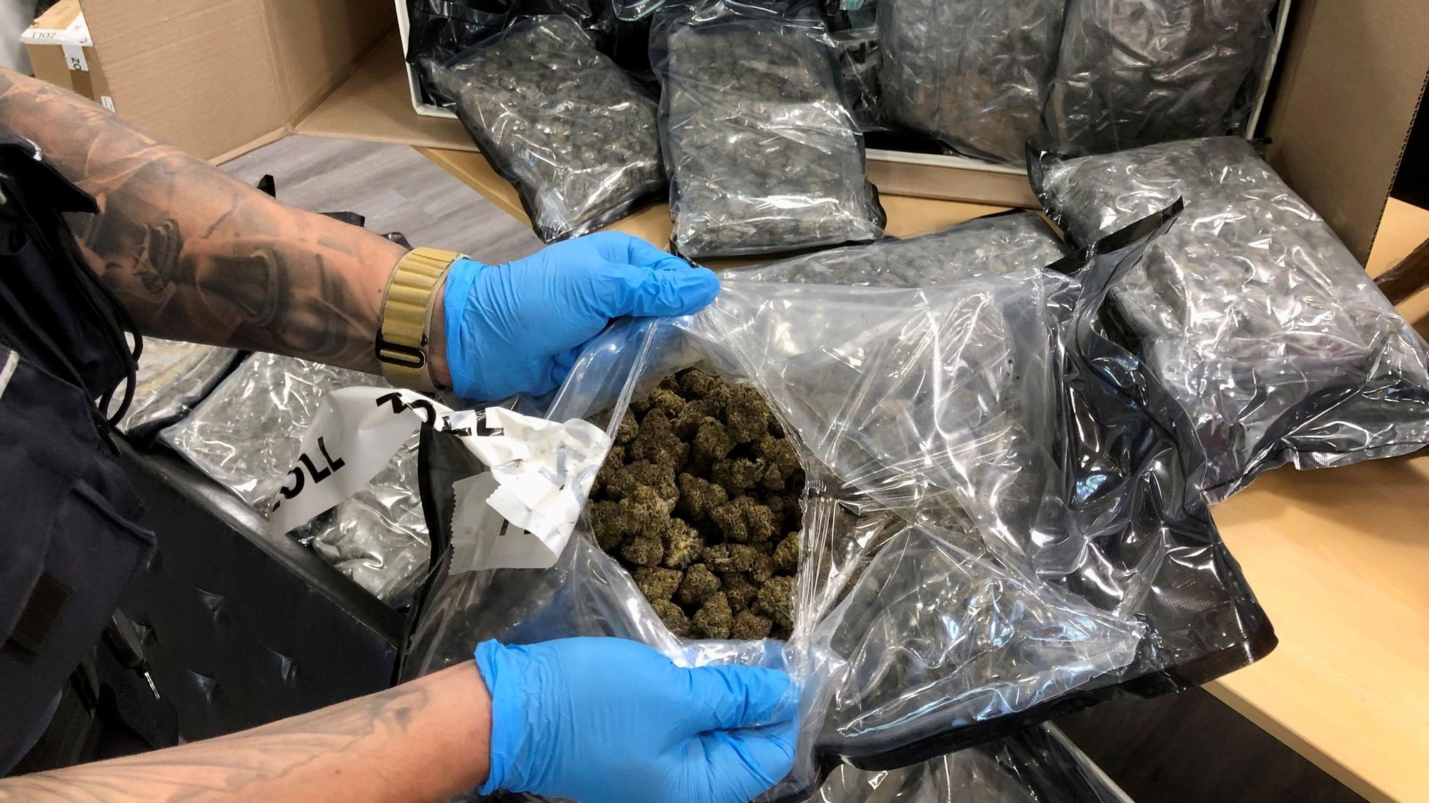 Ein Zollbeamter zeigt einen geöffneten Beutel mit Marihuana.