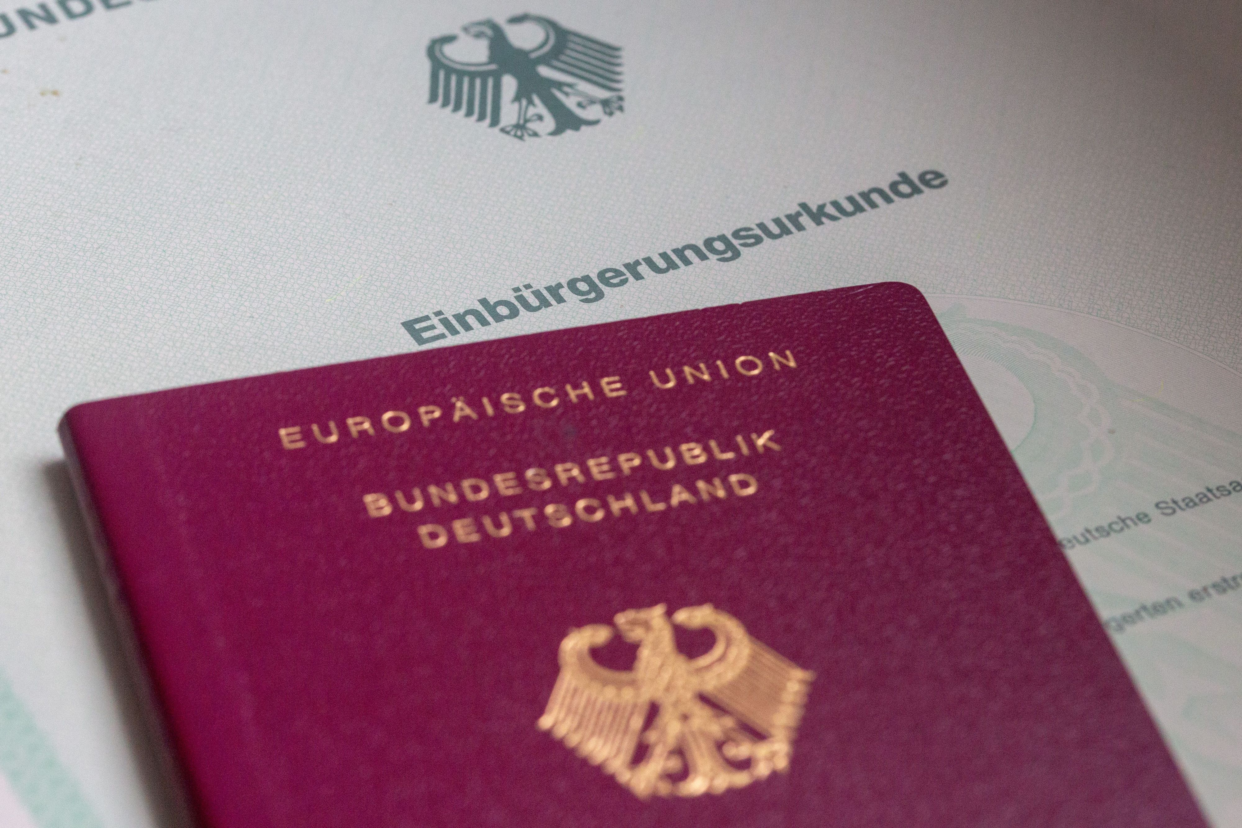 Eine Einbürgerungsurkunde der Bundesrepublik Deutschland und ein deutscher Reisepass liegen auf einem Tisch. (Symbolfoto)