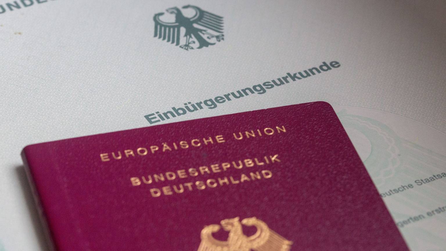Eine Einbürgerungsurkunde der Bundesrepublik Deutschland und ein deutscher Reisepass liegen auf einem Tisch. (Symbolfoto)