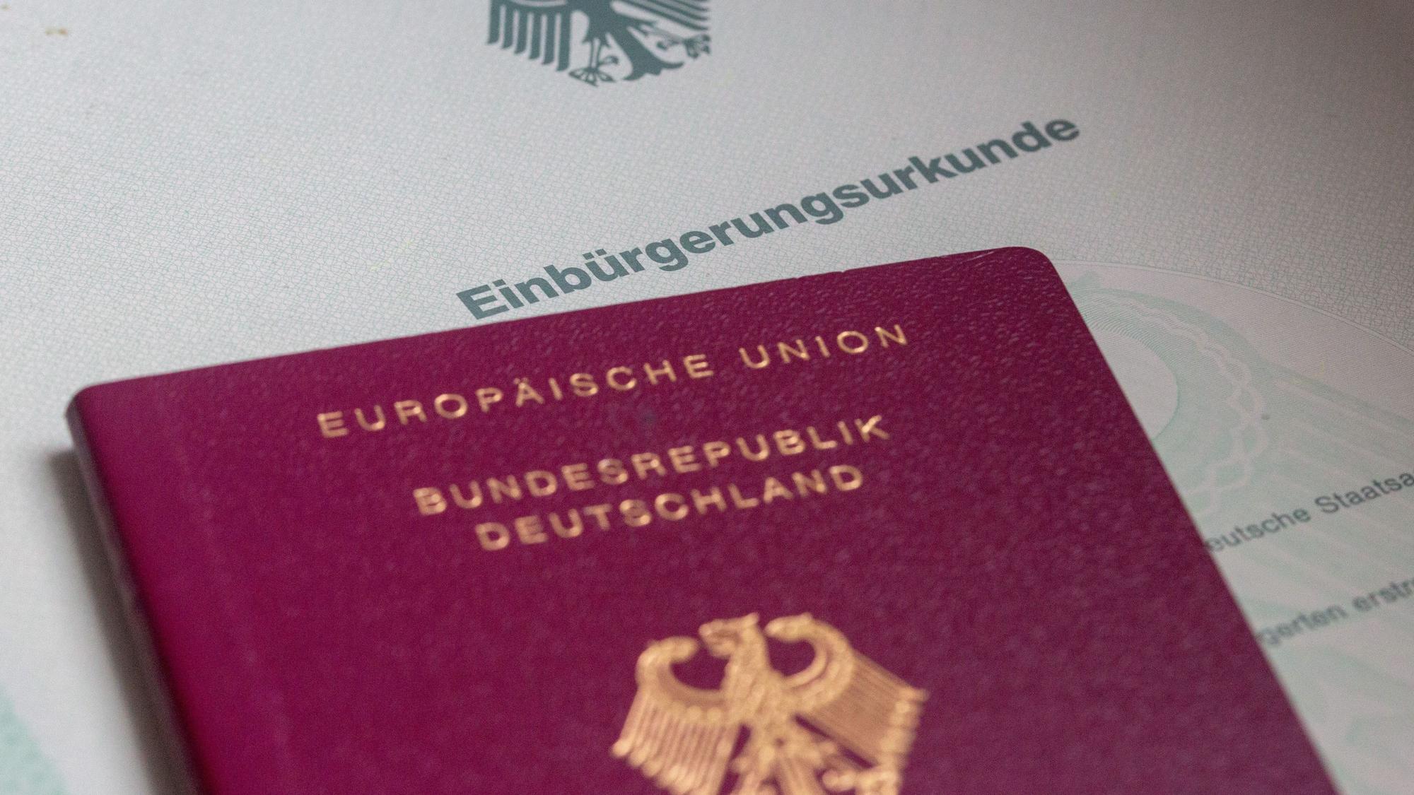 Eine Einbürgerungsurkunde der Bundesrepublik Deutschland und ein deutscher Reisepass liegen auf einem Tisch. (Symbolfoto)