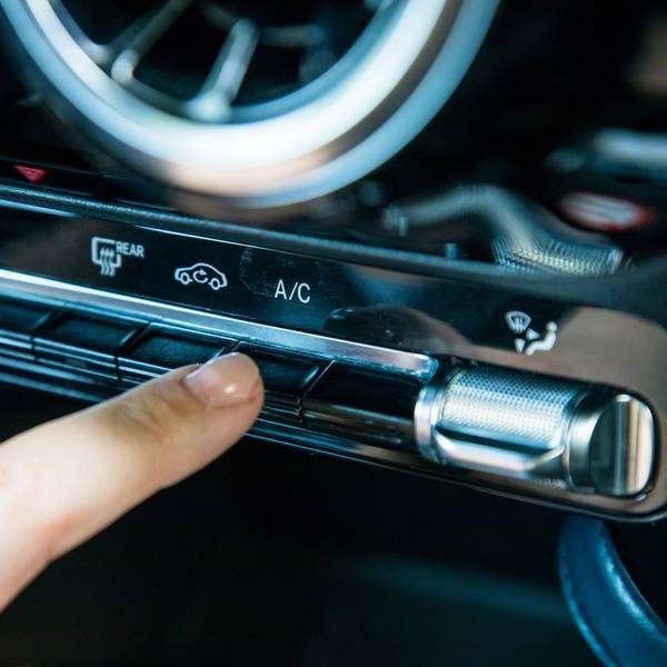 Eine Frau aktiviert die Klimaanlage in einem Auto