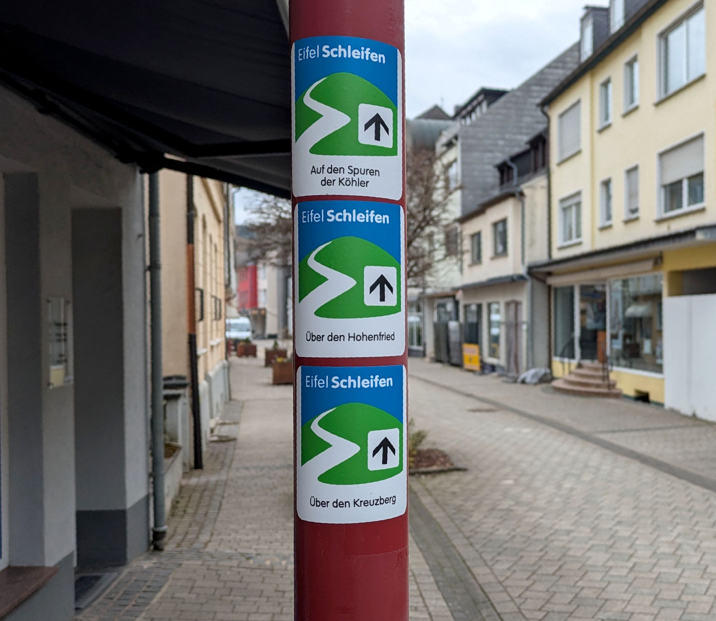 Wegeschilder von drei Eifelschleifen an einem Laternenmast in der Dreiborner Straße in Gemünd.