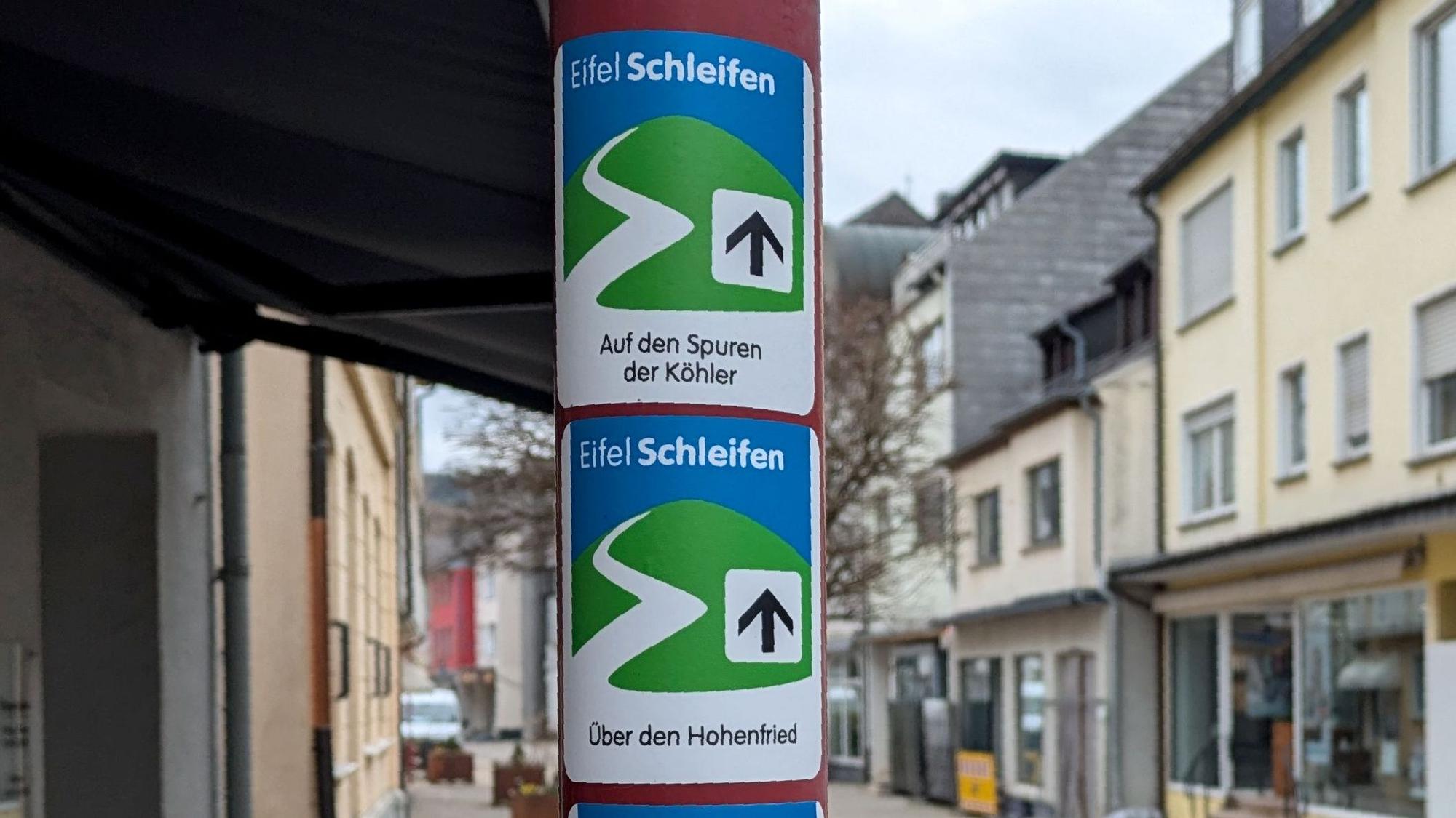 Wegeschilder von drei Eifelschleifen an einem Laternenmast in der Dreiborner Straße in Gemünd.