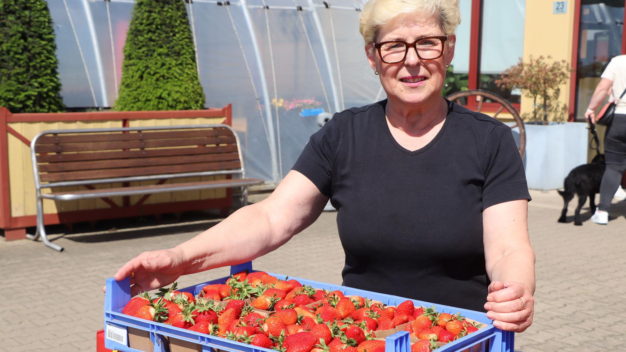 Eine Frau trägt eine Kiste Erdbeeren.