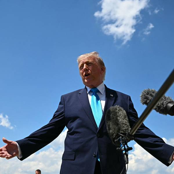 Donald Trump spricht vor blauem Himmel in ein Mikrofon.
