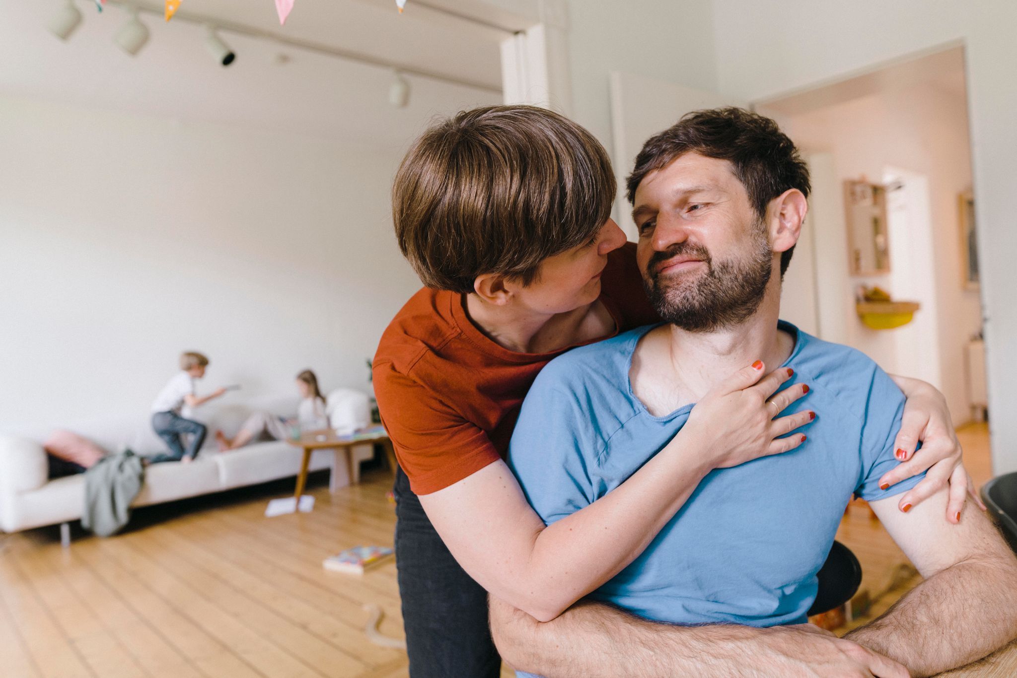 Eltern umarmen sich während Kinder im Hintergrund toben