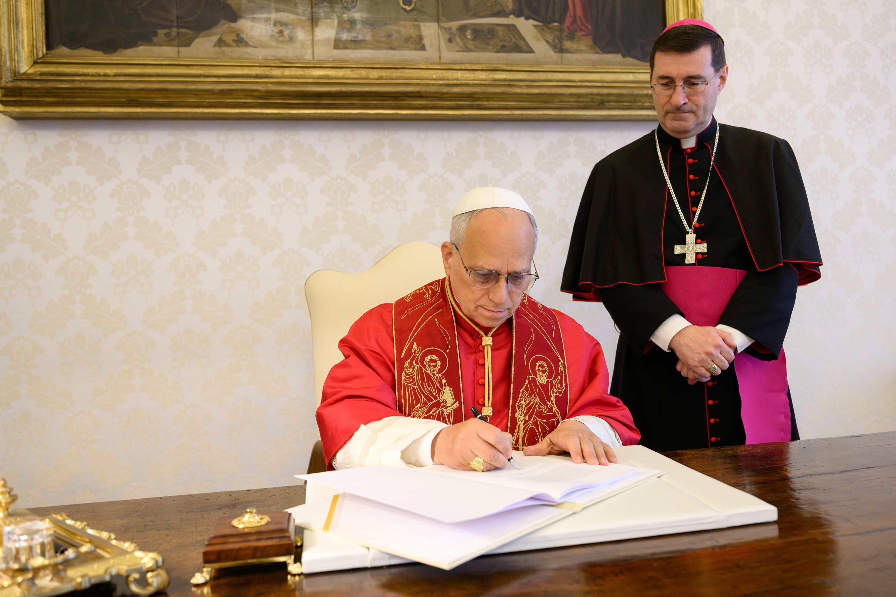 Papst Leo XIV. unterzeichnet die Enzyklika "Magnifica Humanitas - über die Bewahrung des Menschen im Zeitalter der Künstlichen Intelligenz" am 25. Mai 2026 im Vatikan. Rechts im Bild: Erzbischof Paolo Rudelli, Substitut für Allgemeine Angelegenheiten des Staatssekretariats. Weitere Berichterstattung bei KNA.