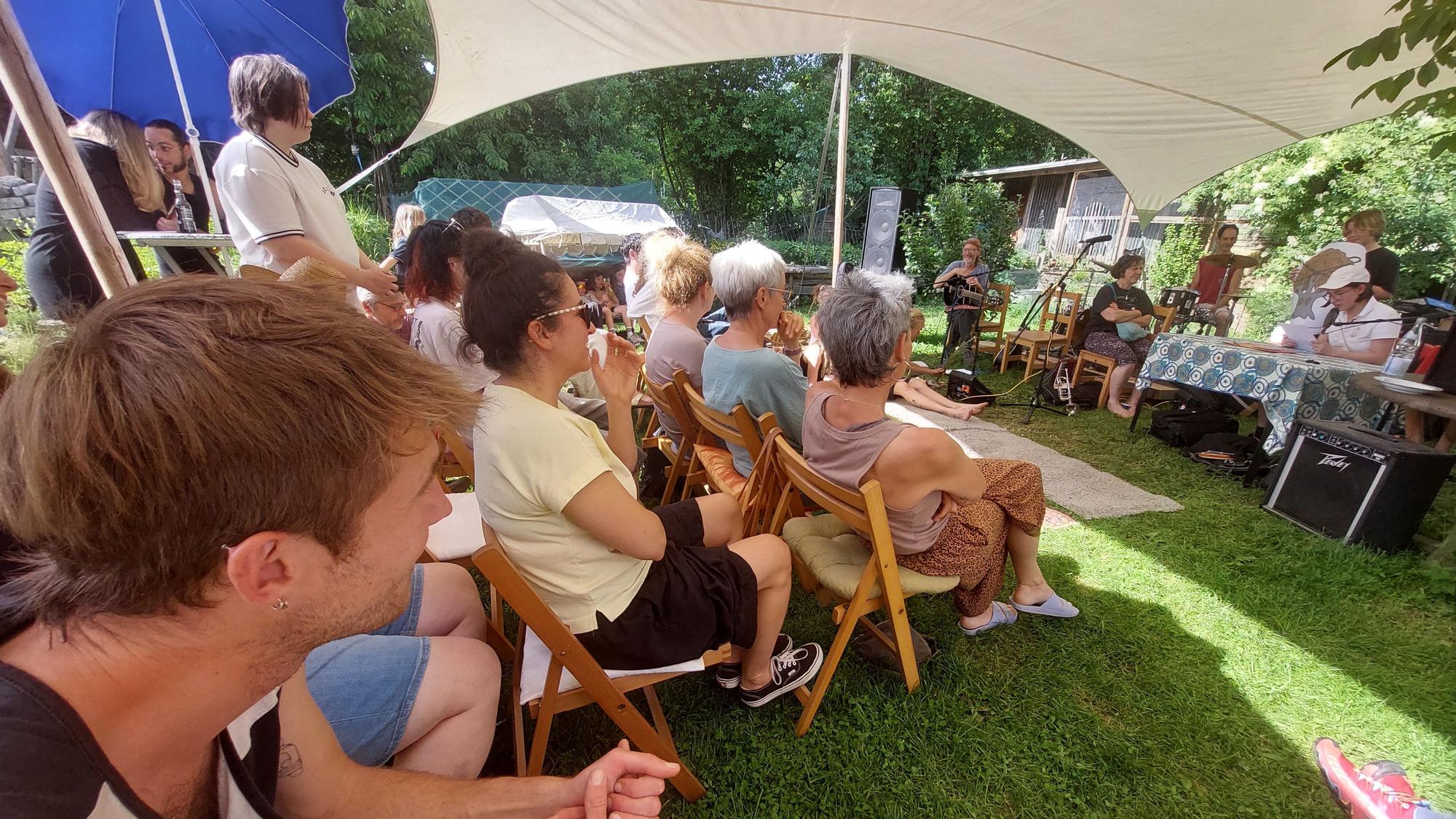 Das Publikum im Kulturhafen Au hört unter Sonnensegeln den Geschichten zu.