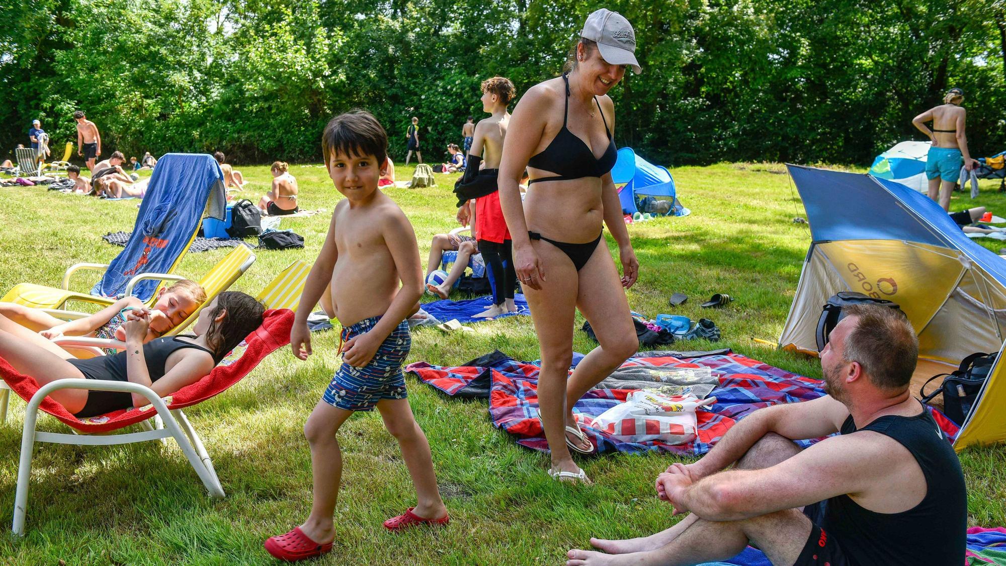 Das Foto zeigt eine Familie auf der Wiese am Freibad.