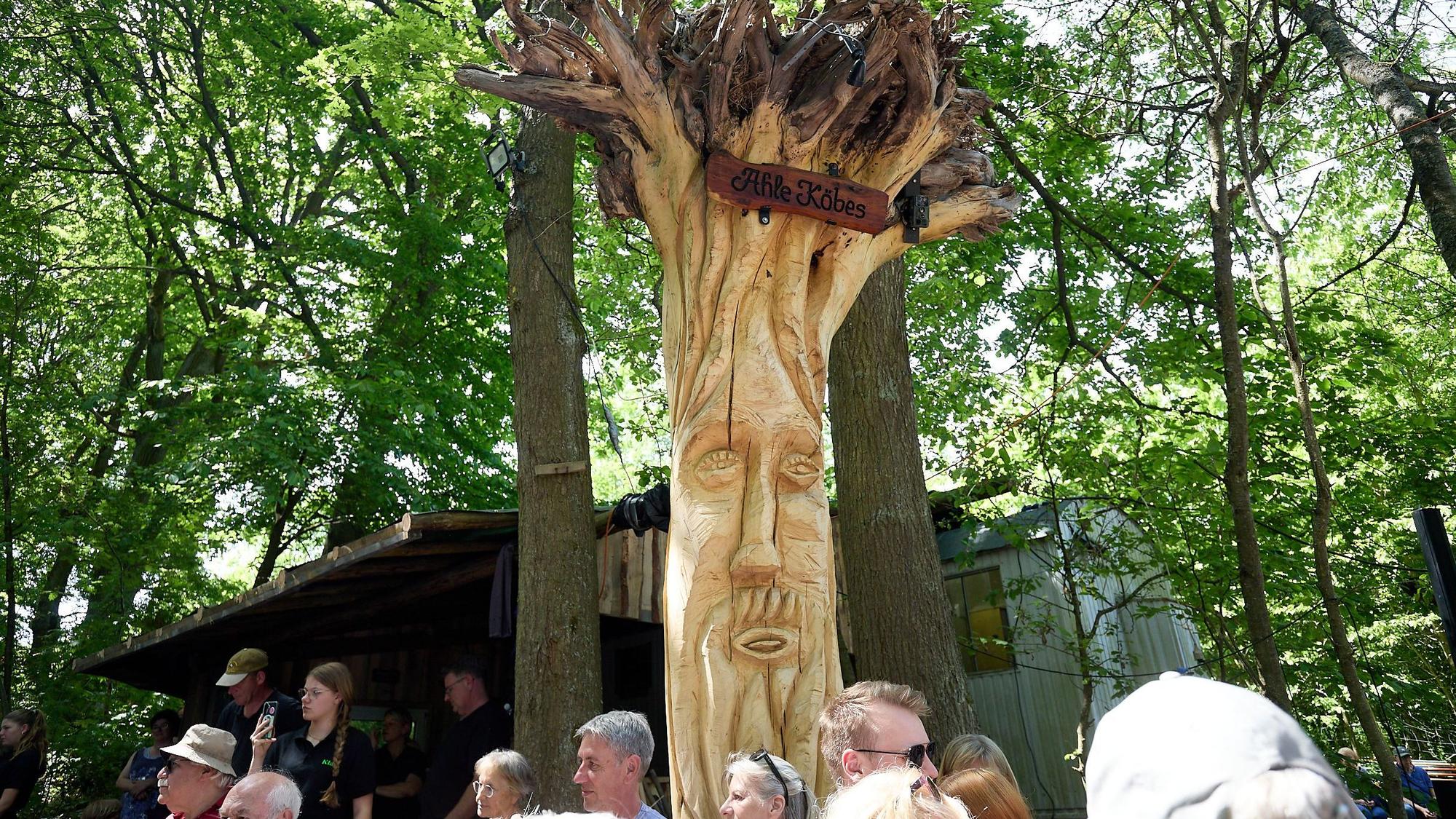 Das Bild zeigt einen hohen Baumstamm, in den ein Gesicht gehauen wurde.