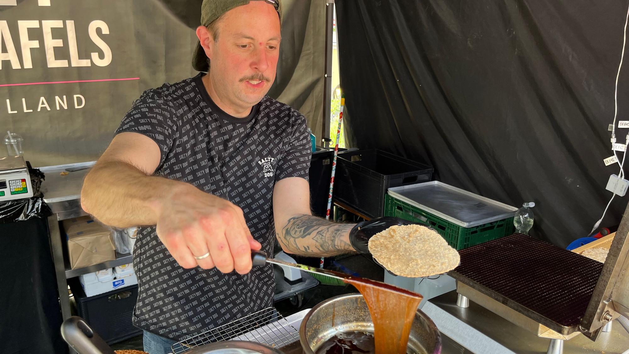 Zu sehen ist ein Mann, der Waffeln mit Sirup bestreicht.