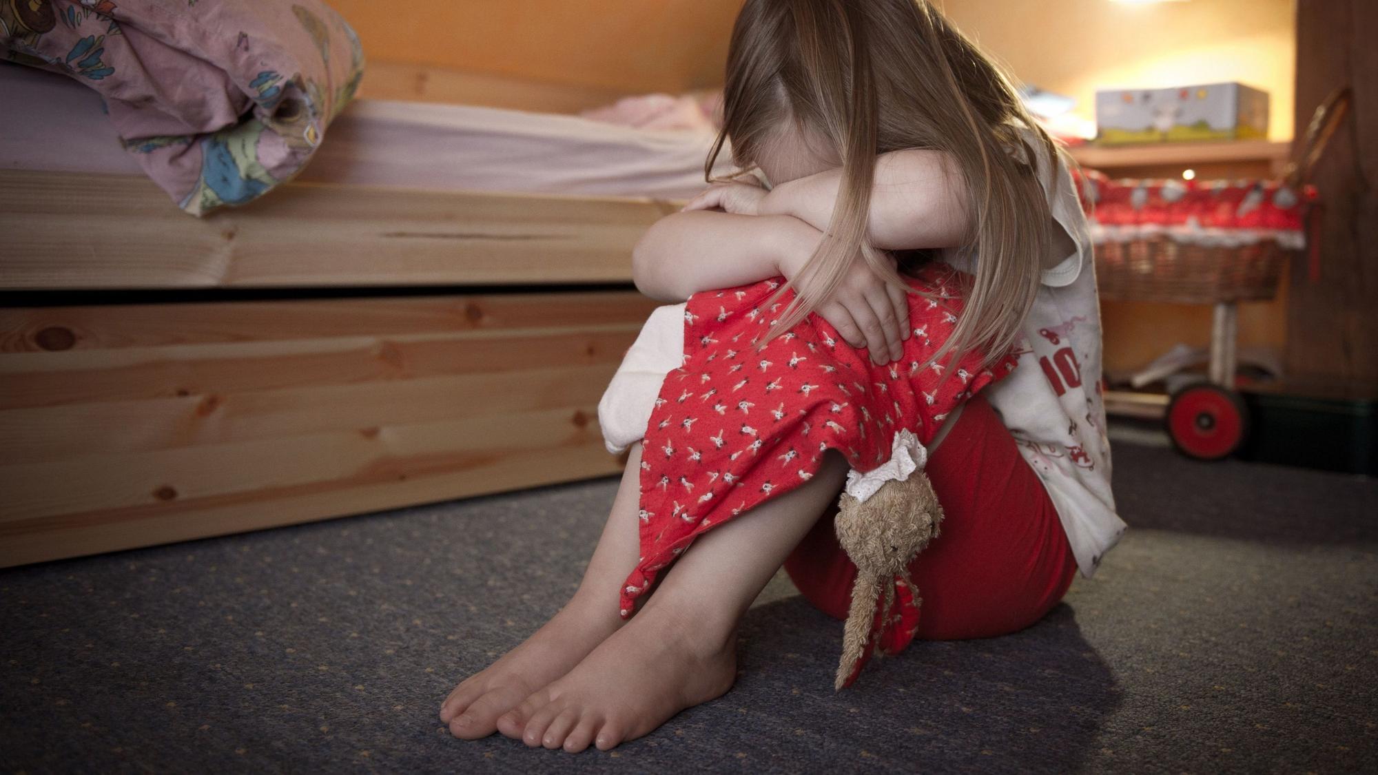 Ein kleines Mädchen sitzt weinend auf dem Fußboden in ihrem Zimmer. NRW will Opfer von Straftaten künftig besser vor Re-Traumatisierungen schützen.