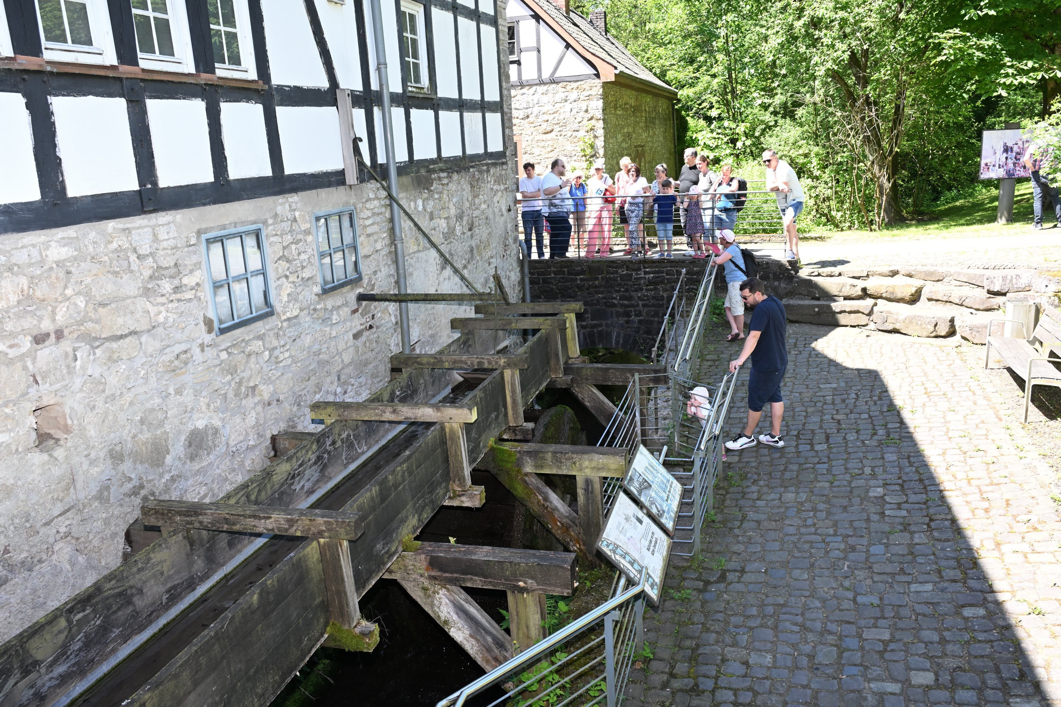 Zu sehen ist eine Gruppe mit einem Museumsguide an einer alten Mühle.