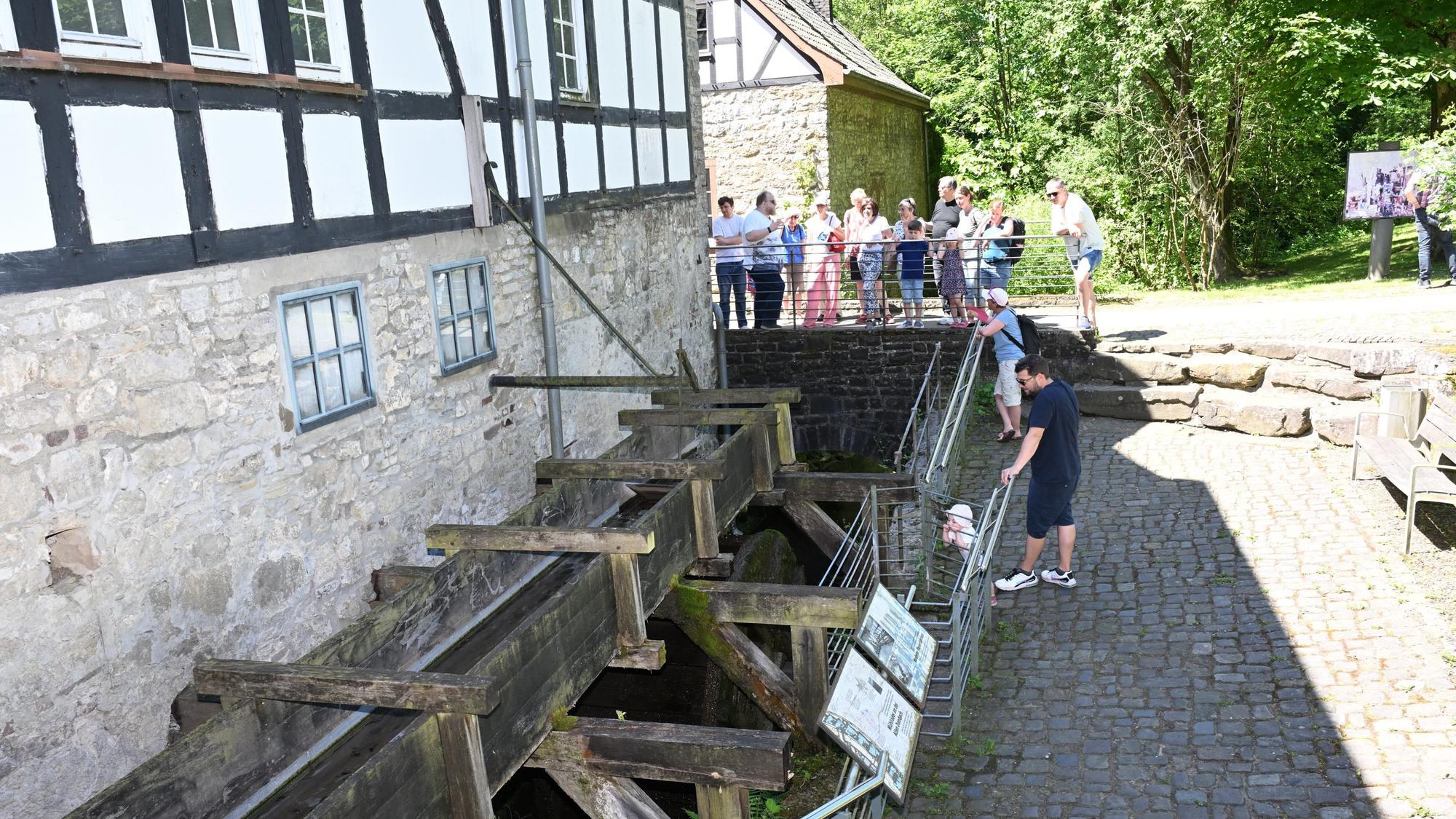 Zu sehen ist eine Gruppe mit einem Museumsguide an einer alten Mühle.