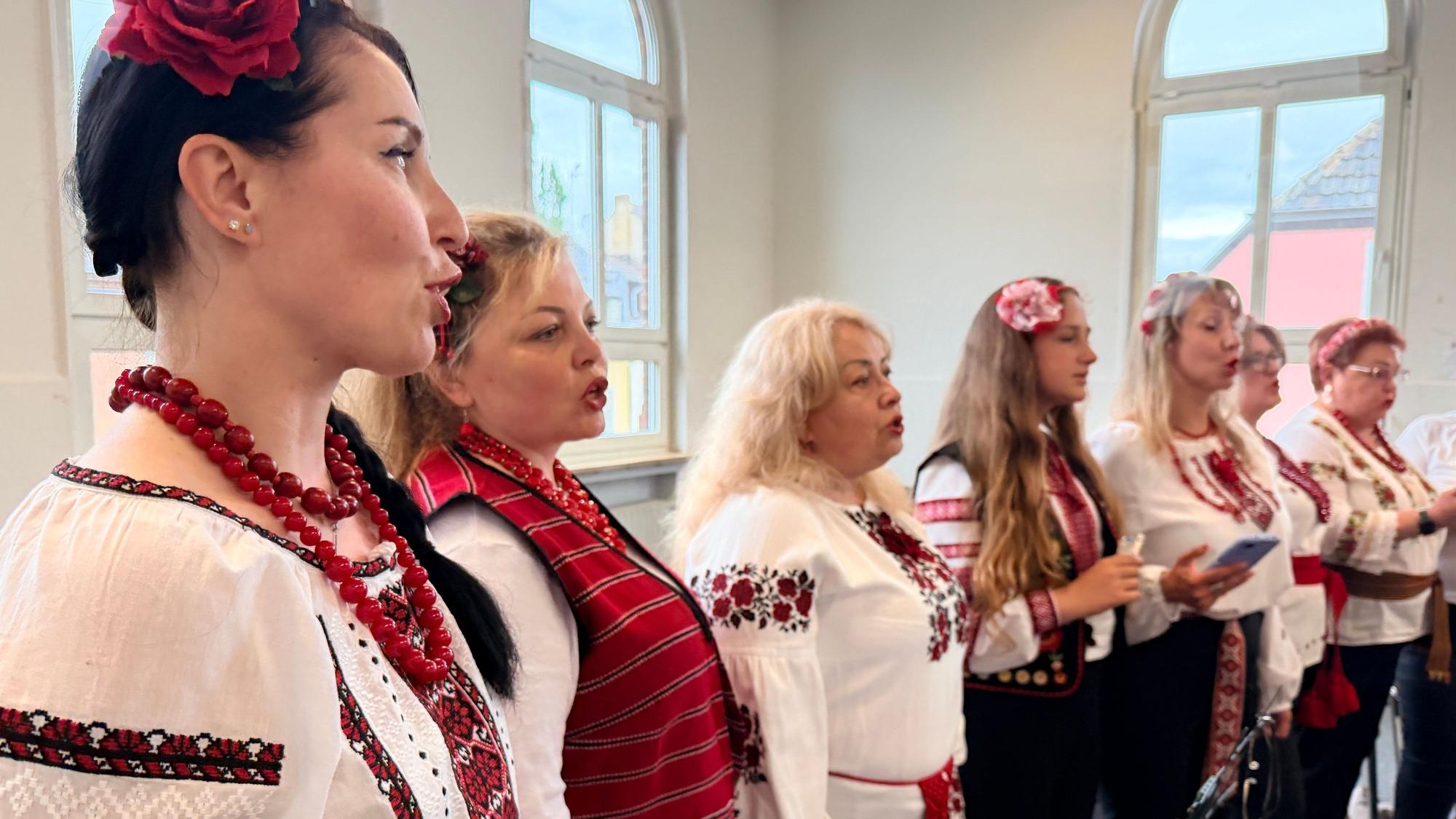 Die Sängerinnen stehen nebeneinander. Sie tragen die bestickten folkloristischen Kleider der Ukraine.