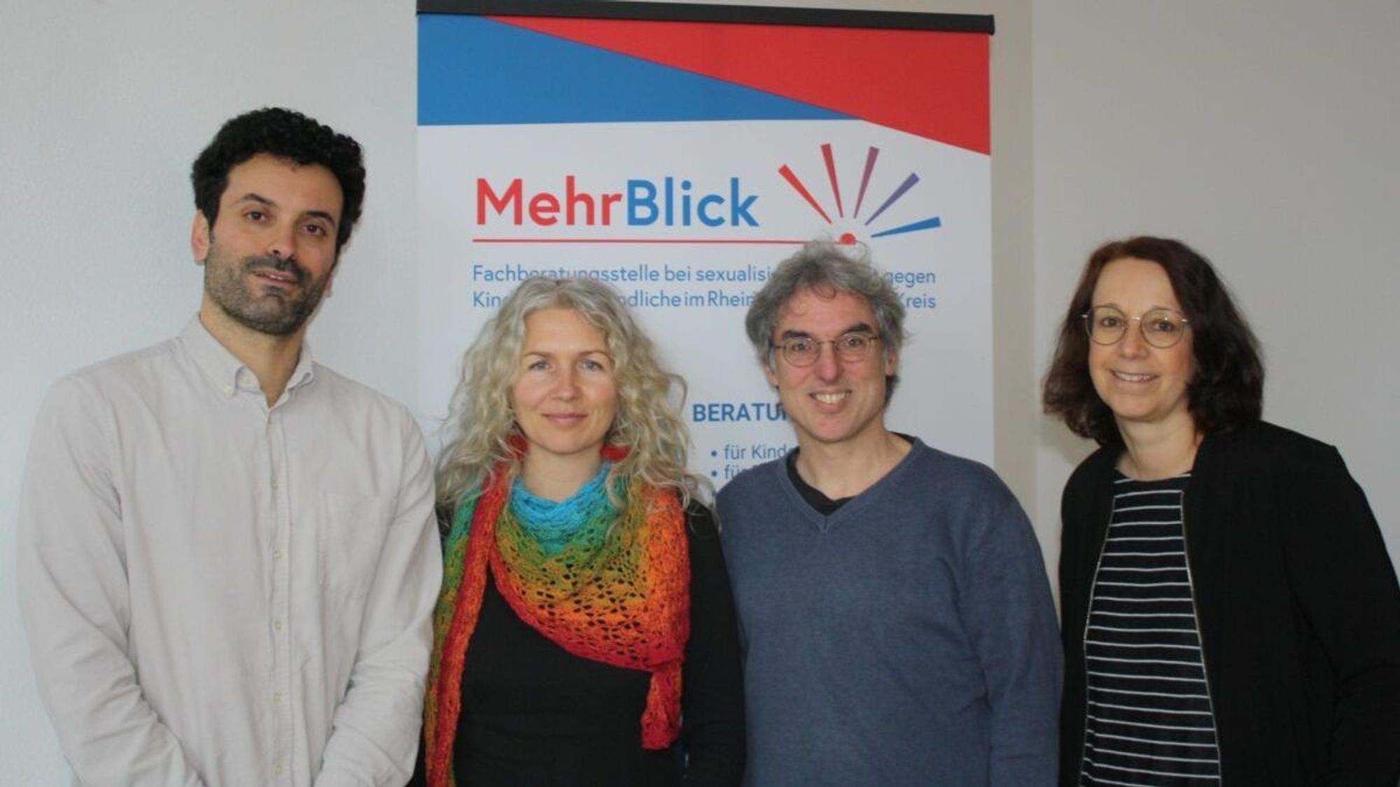 Das Team von Mehrblick steht vor einem Banner.