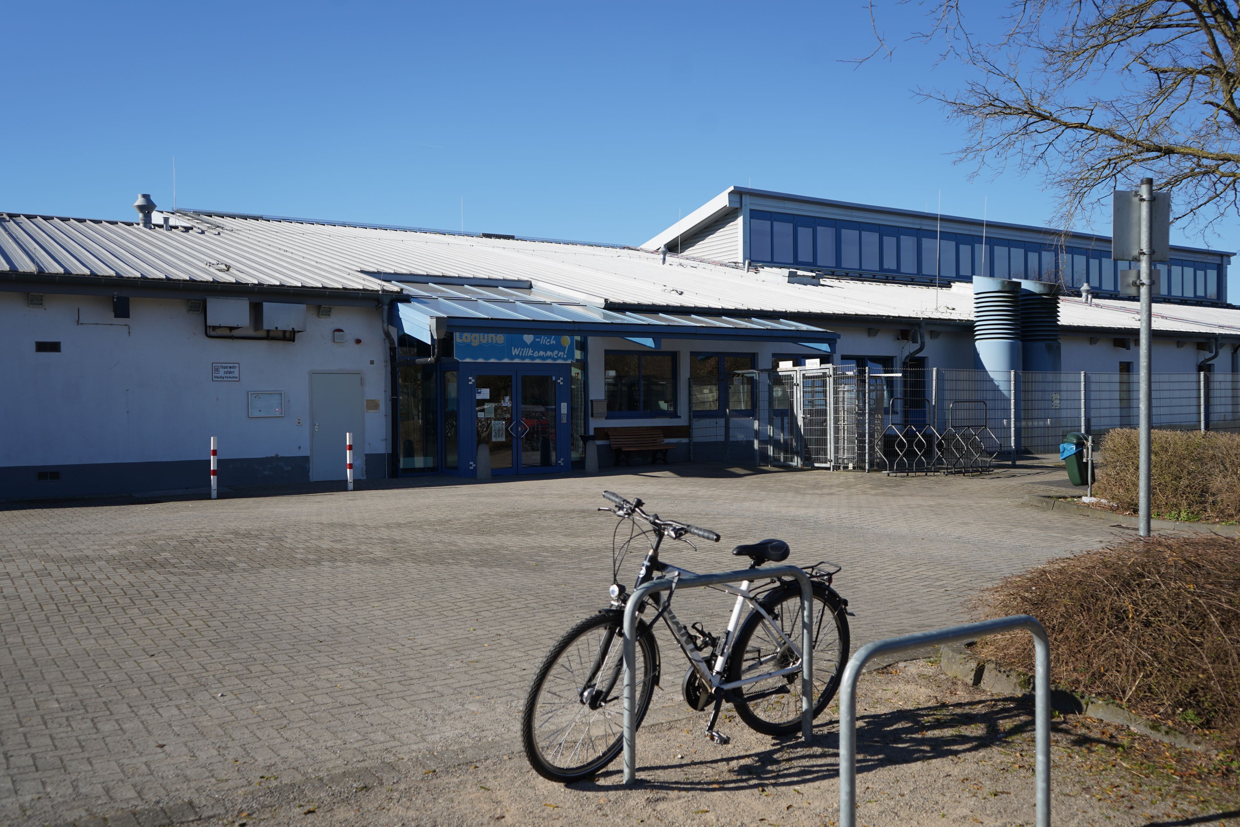 Das Foto zeigt ein Schwimmbad von außen, davor ein Fahrrad.