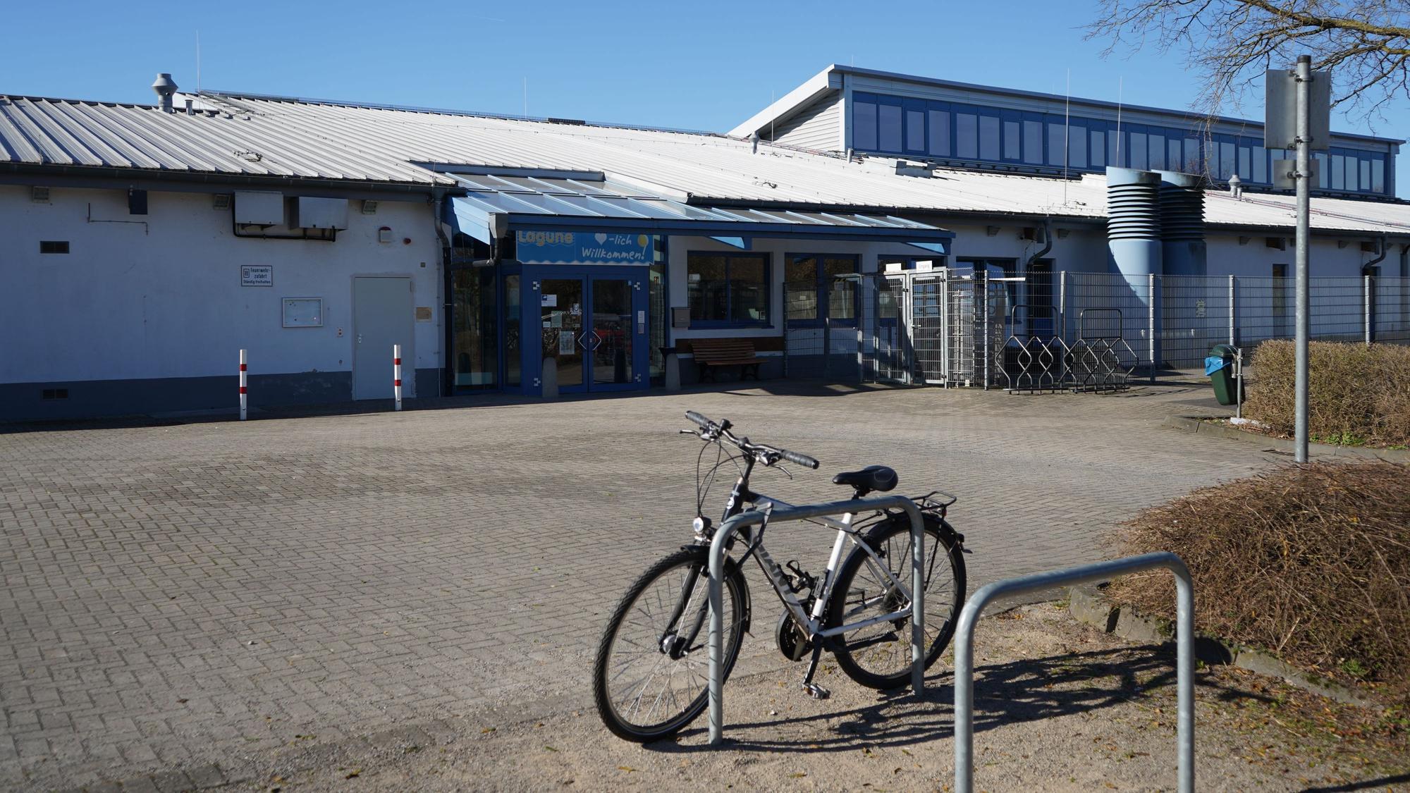 Das Foto zeigt ein Schwimmbad von außen, davor ein Fahrrad.