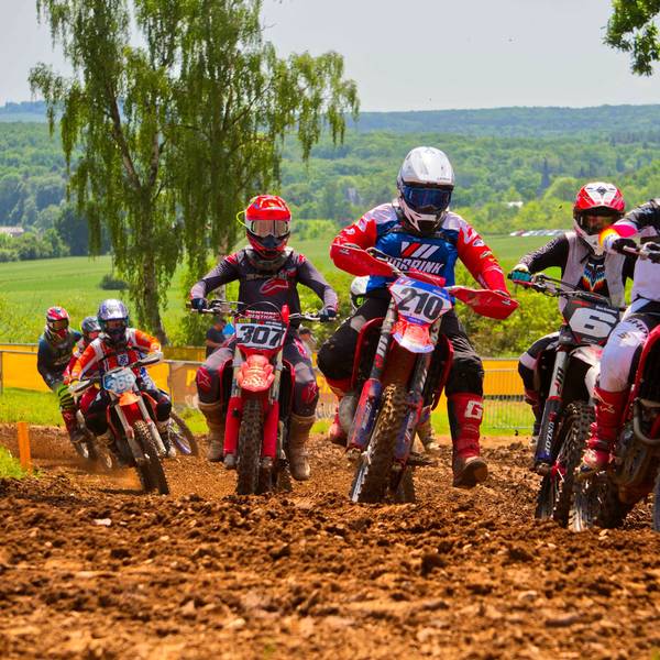 Motocross-Fahrer hinter- und nebeneinander fahren über eine schlammige Strecke.