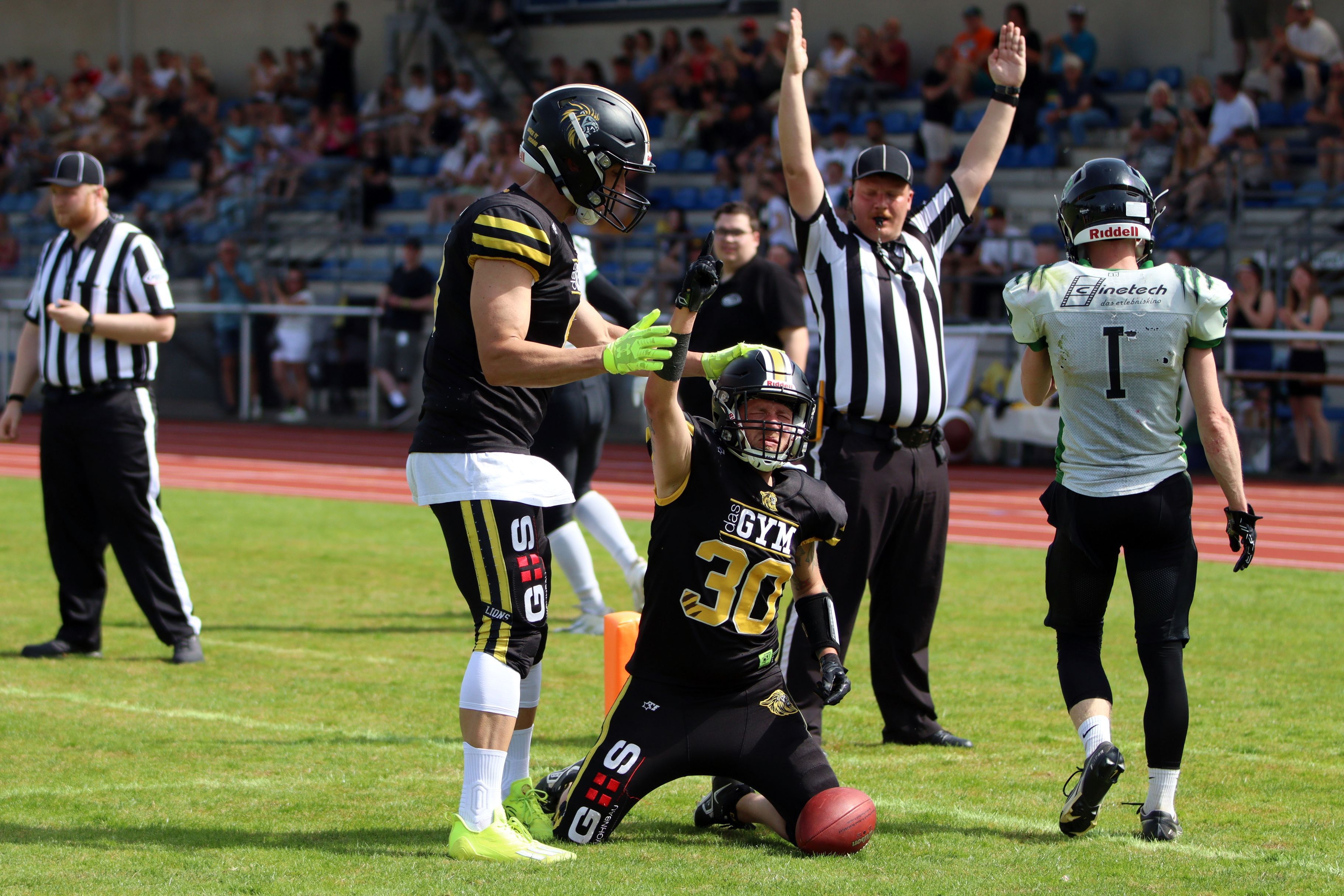 Ein Footballer jubelt über einen Touchdown, ein Mitspieler legt ihm die Hand auf den Helm.