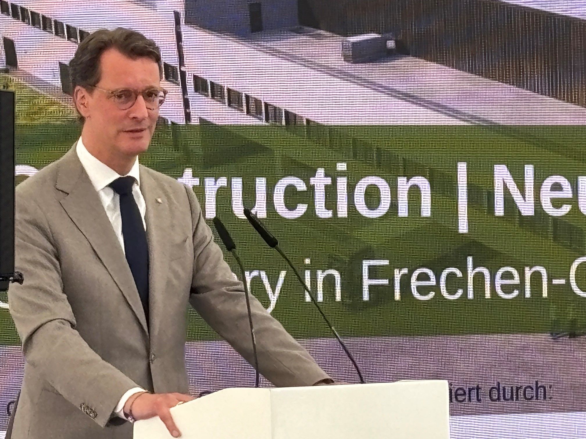 Auf dem Bild ist der NRW-Ministerpräsident Hendrik Wüst zu sehen, der in Frechen eine Rede hält.