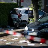 Ein Schulrucksack liegt auf dem Boden vor beschädigten Autos. Die Polizei sichert eine Unfallstelle, nachdem eine Autofahrerin drei Kinder vor einer Schule in Dinslaken verletzt hat.