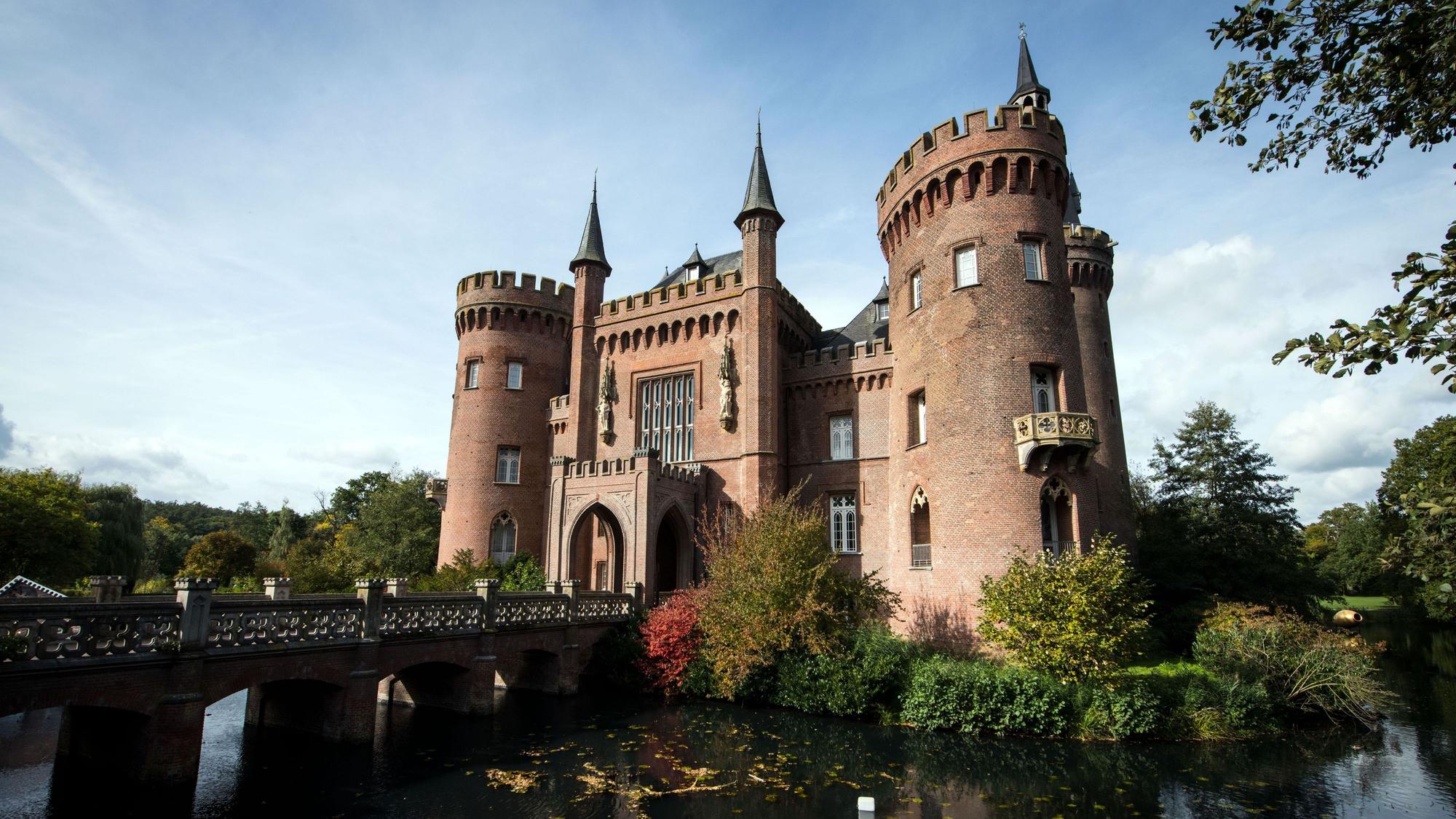 Schloss Moyland am Niederrhein von außen mit Brücke und Gewässer.