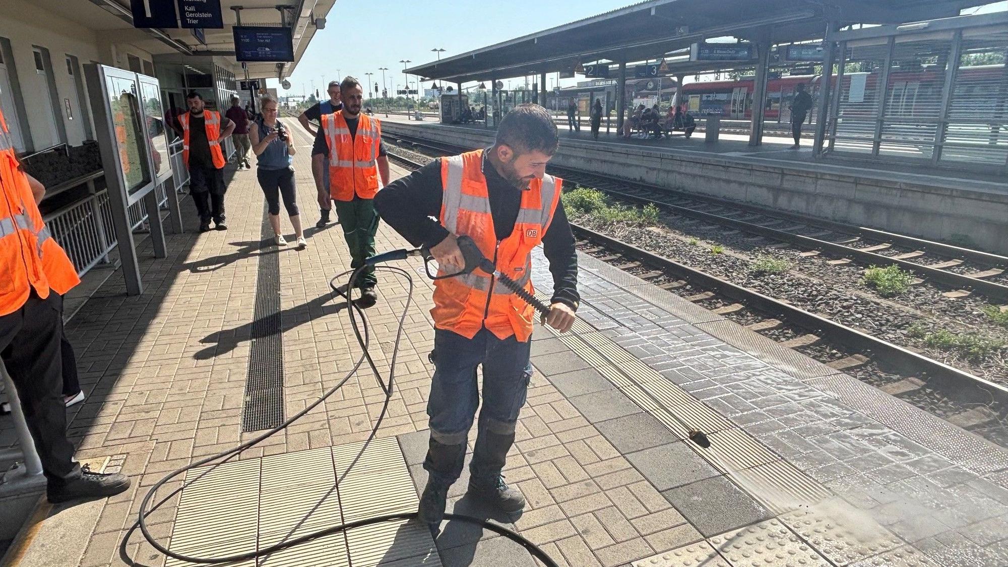 Mit einem Hochdruckreiniger säubert ein Mitarbeiter den Bahnsteig in Euskirchen.