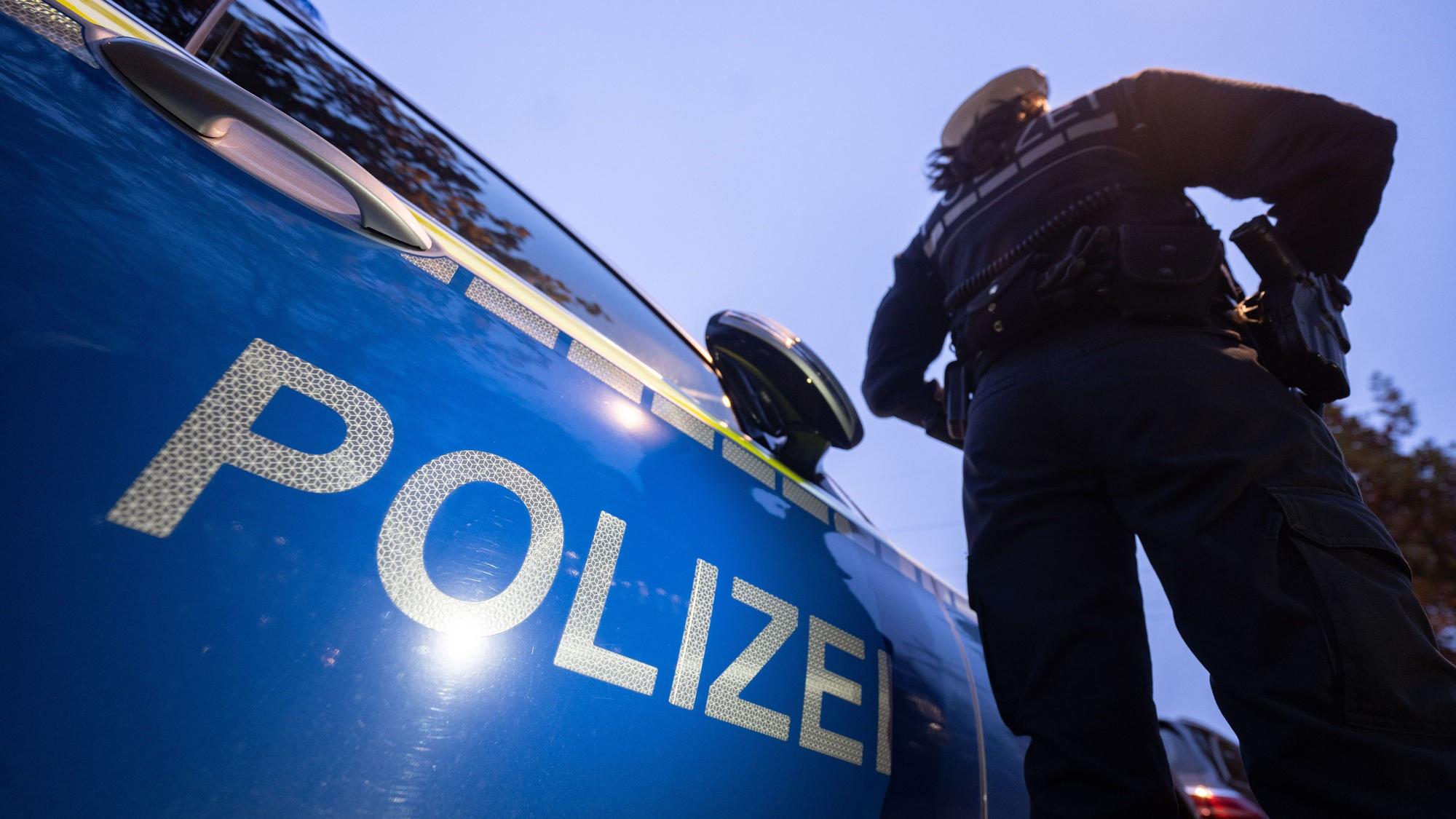 Eine Polizistin steht neben einem Polizeifahrzeug.