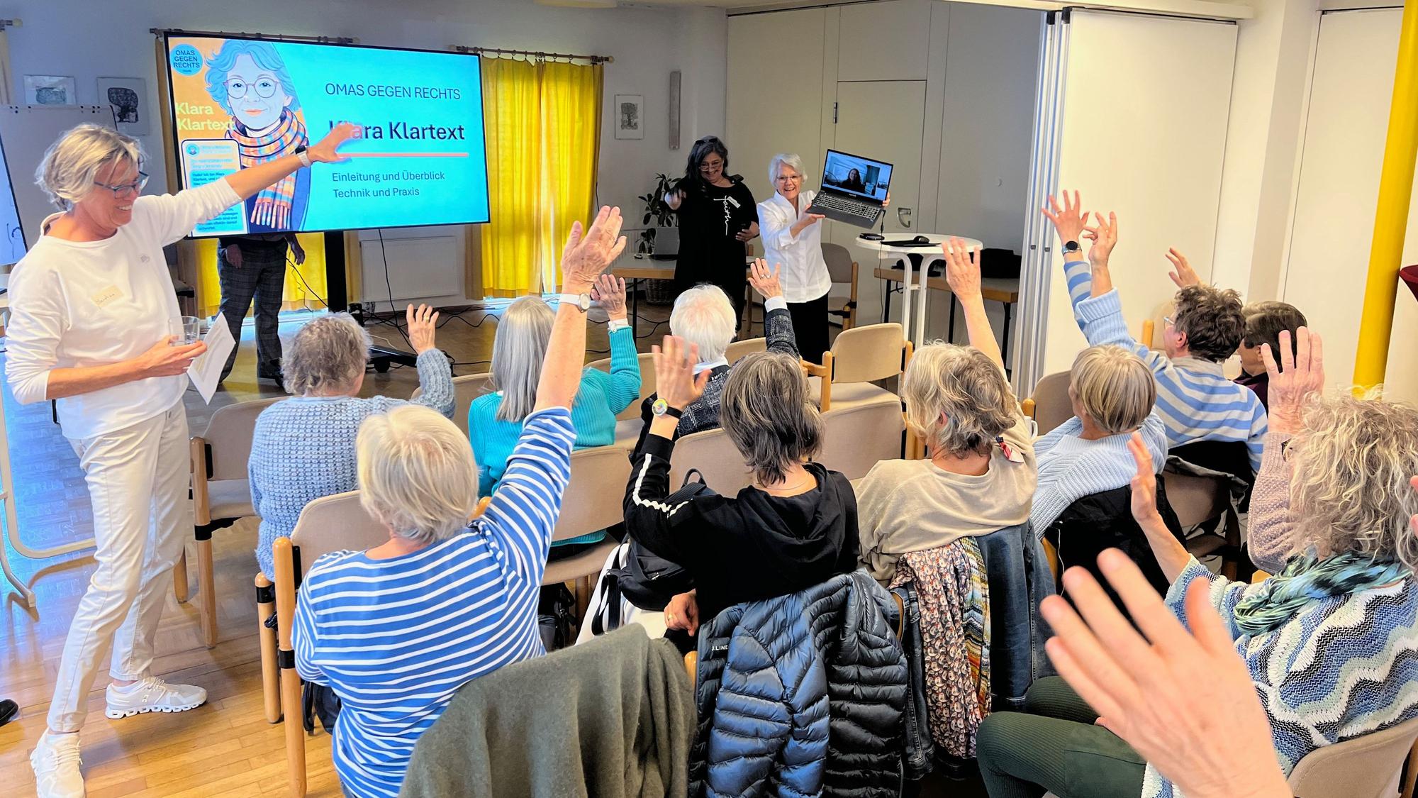 Das Foto zeigt die Erfinder von „Klara Klartext“ vor Gästen im Gemeindesaal in Efferen.