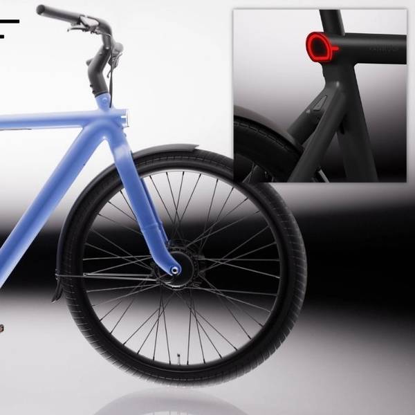 VanMoof S6 E-Bike in der Seitenansicht in der Farbe Drift Black vor hellem Hintergrund, mit Detailaufnahme des nahtlos in den Aluminiumrahmen integrierten Rücklichts in der Farbe Electric Blue – sichtbar auch das integrierte Frontlicht am Vorderrad.
