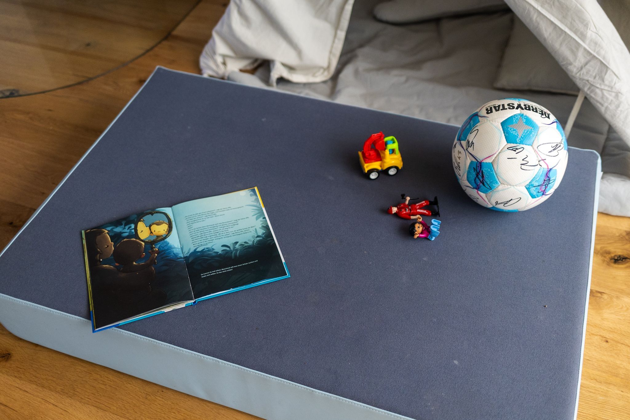 Ein Buch liegt aufgeschlagen auf einer Matte, daneben ein unterschriebener Fußball.