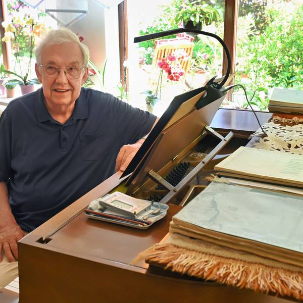 Paul F. Irmen sitzt in seinem Wohnzimmer in Marmagen an einem Klavier. Darauf liegen zahlreiche Notenbücher.