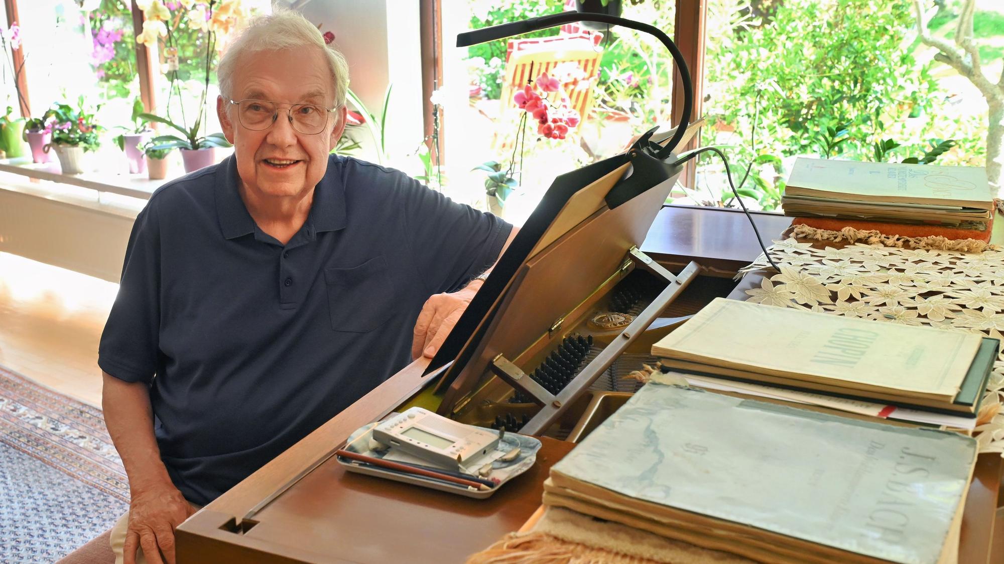 Paul F. Irmen sitzt in seinem Wohnzimmer in Marmagen an einem Klavier. Darauf liegen zahlreiche Notenbücher.