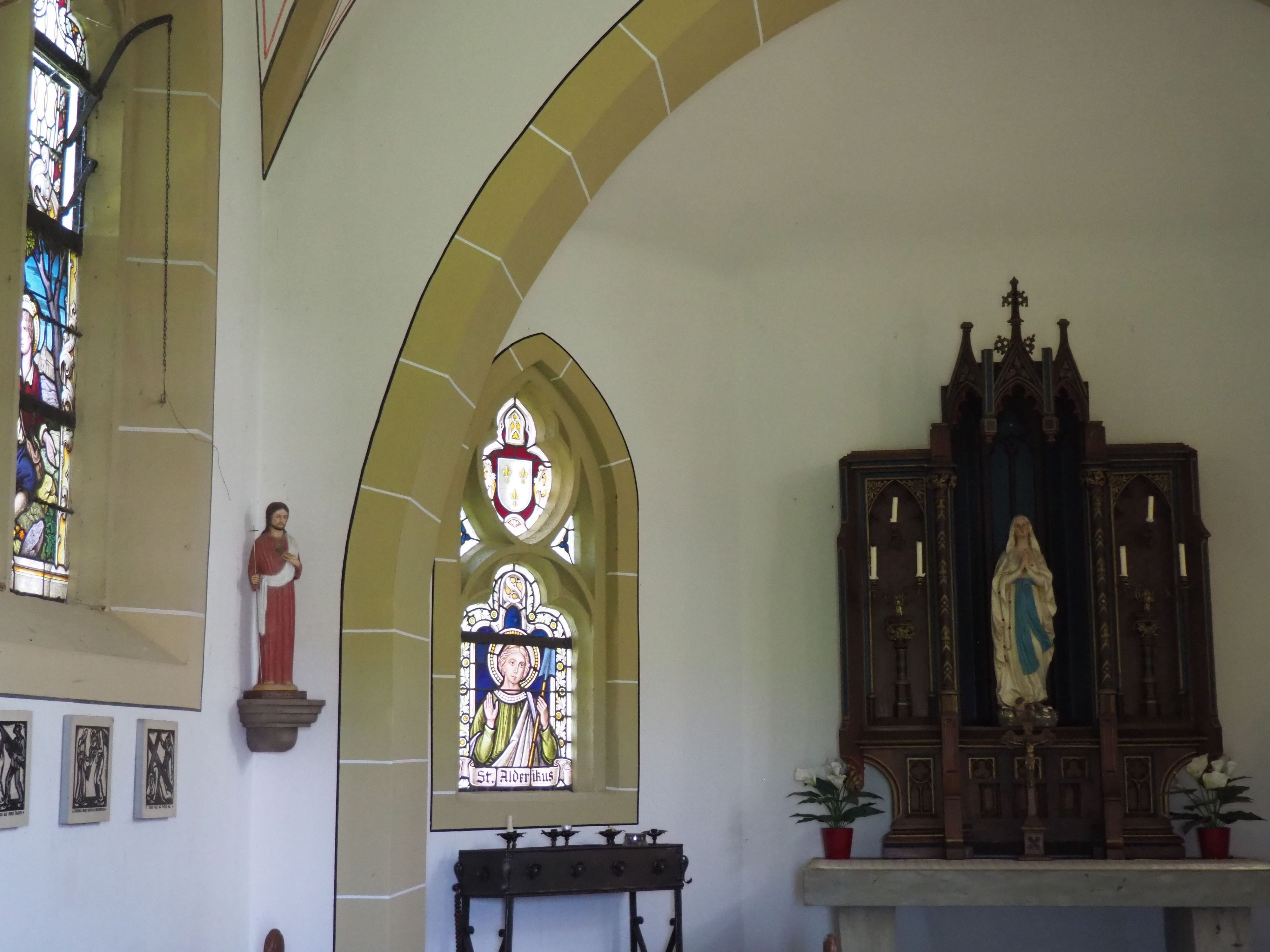 Das Bild zeigt das Innere der Kirche. Links befindet sich das Fenster mit der Darstellung des Alderikus, rechts daneben der Altar,