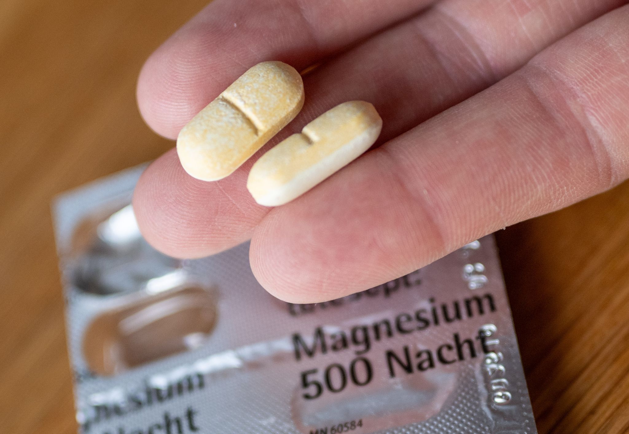 Ein Mann hält zwei Magnesium-Tabletten auf der Hand