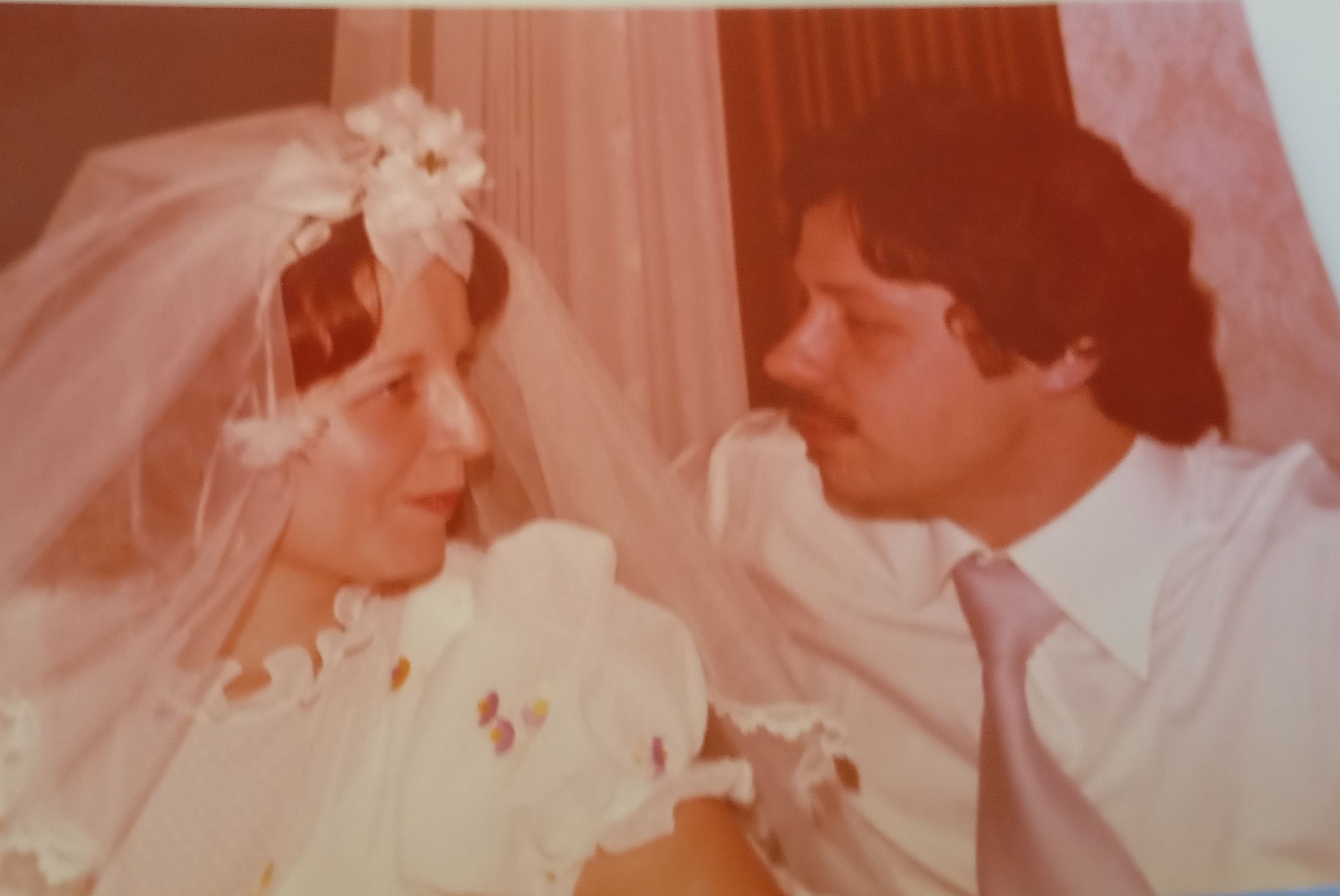 Zu sehen sind eine Braut und ihr Bräutigam an ihrem Hochzeitstag.