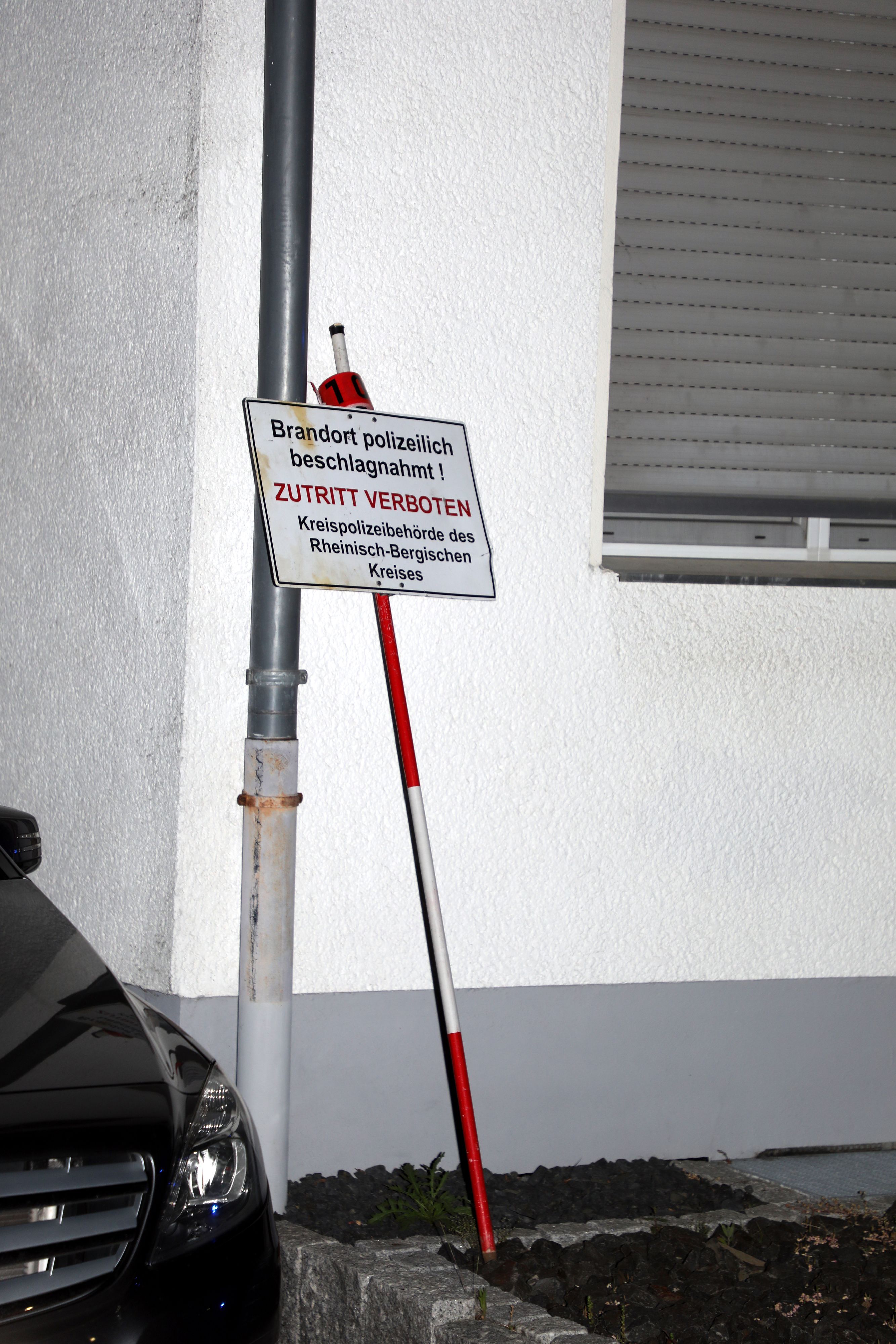 Ein Polizeischild lehnt an einem Mehr-Parteien-Haus in Bergisch Gladbach-Lustheide.