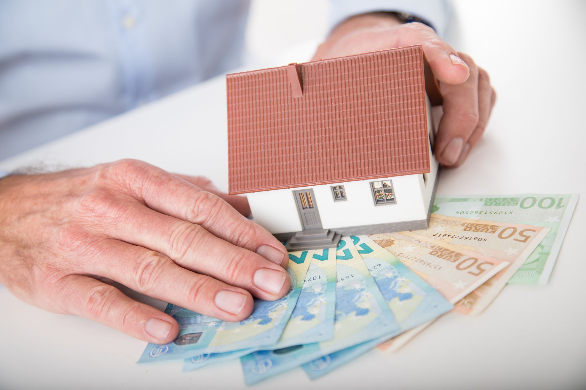 Ein Mann hält das Modell eines Hauses in den Händen