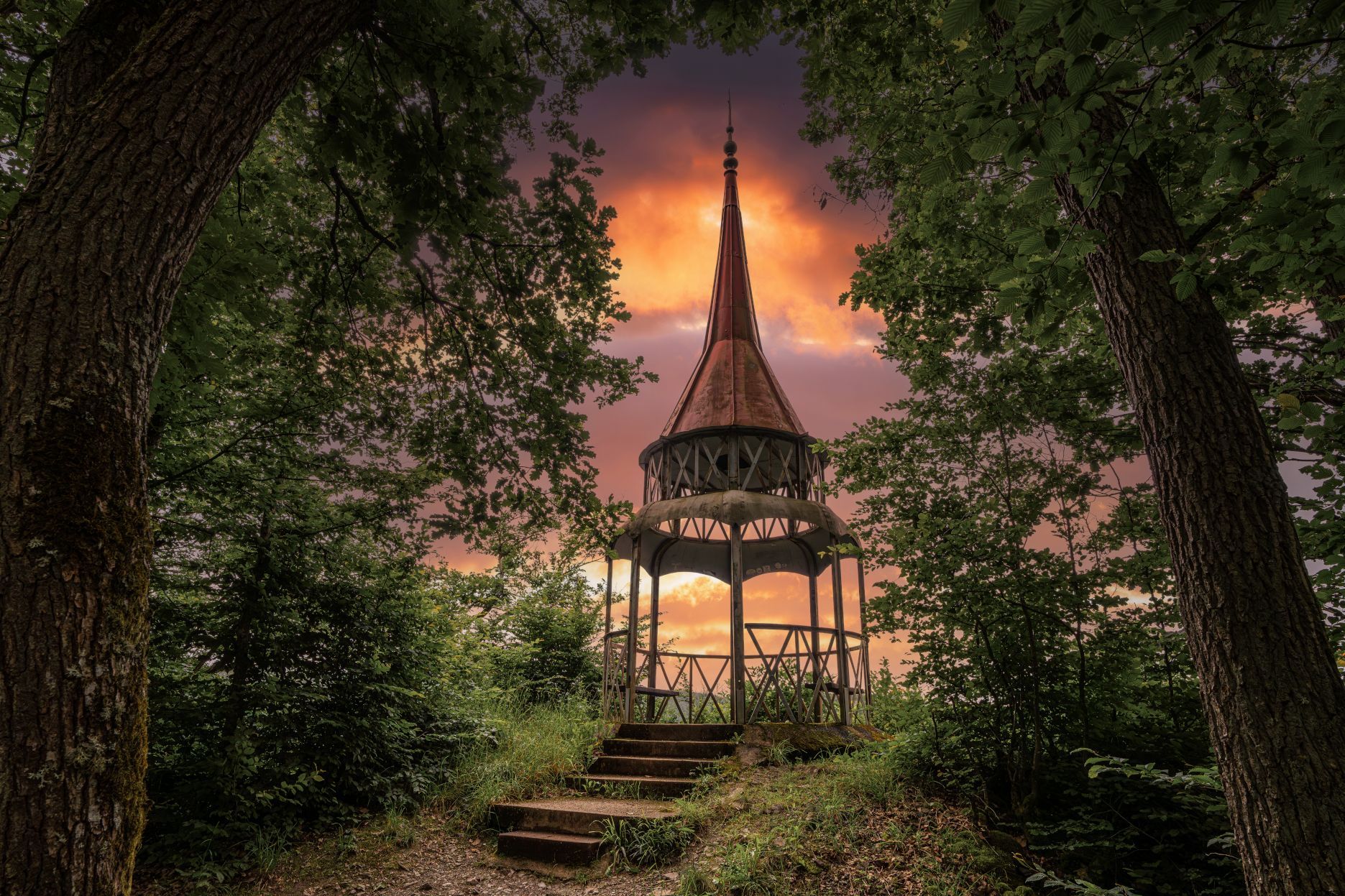 Der Hohenzollernzurm bei Bad Bertrich in der Eifel ist vor einem in spektakulären Orangetönen gefärbten Himmel zu sehen.