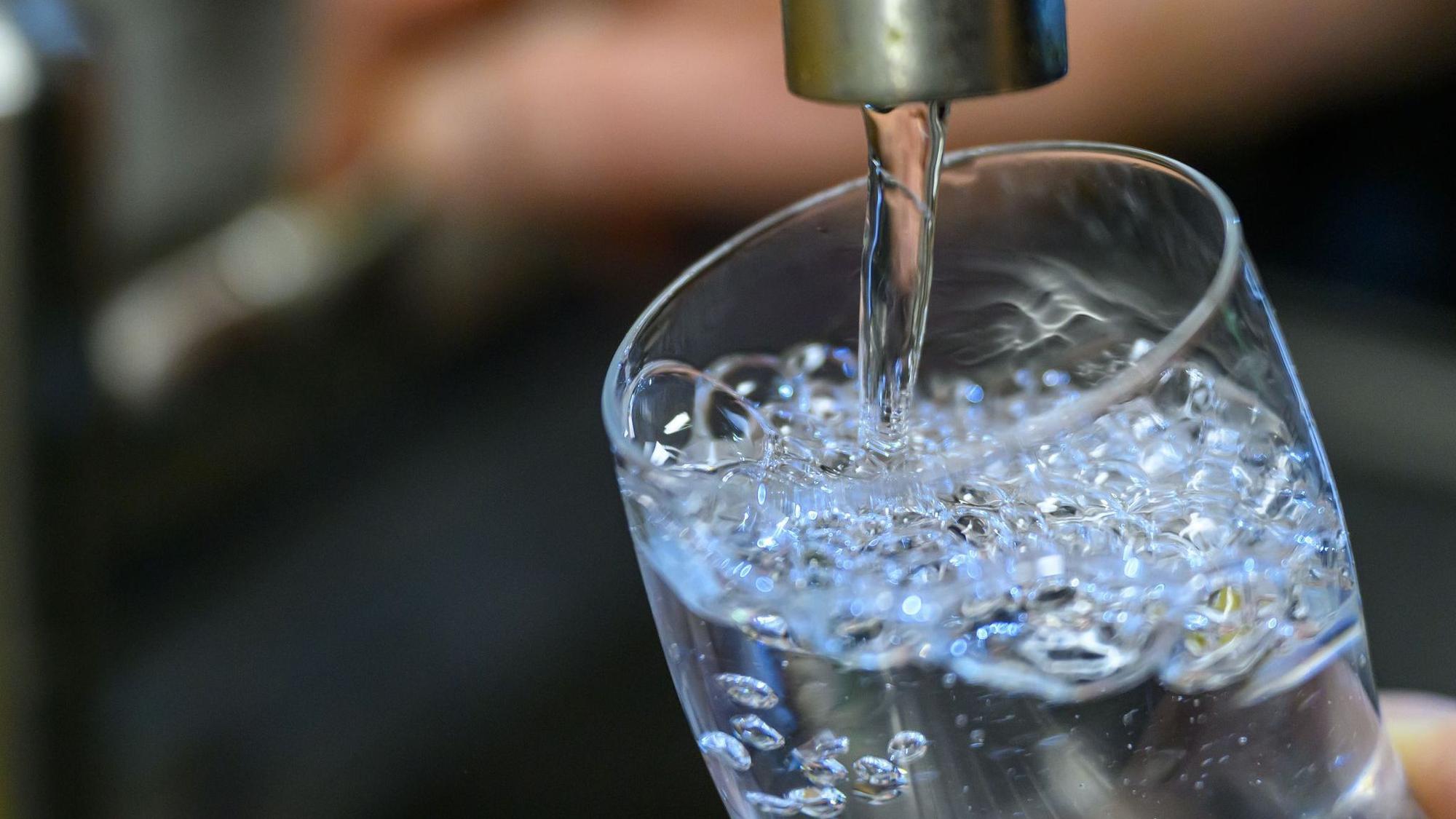 Trinkwasser läuft aus einem Wasserhahn in ein Glas.