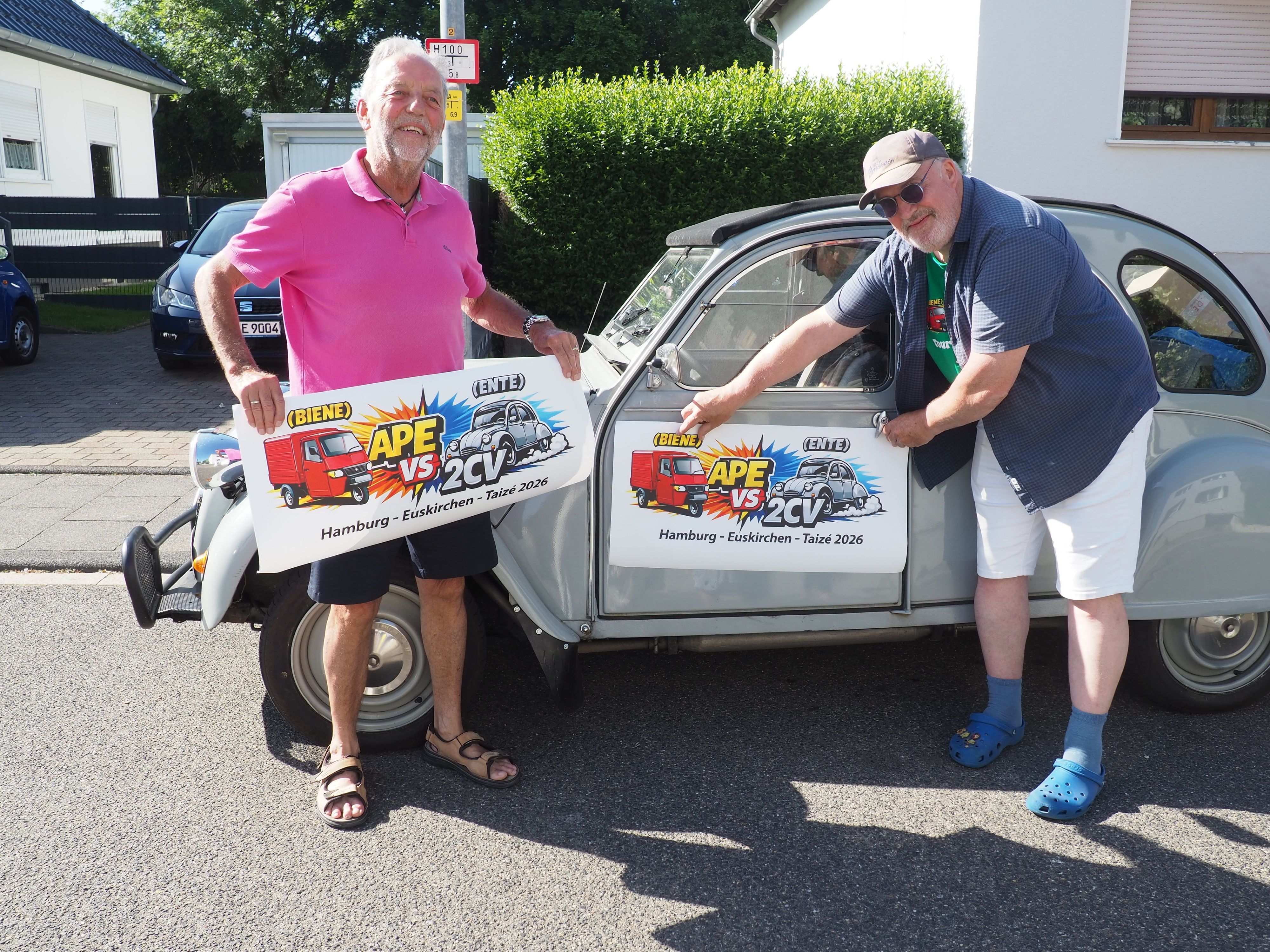 Gerd Weinand und Torsten Pormann kleben ein Plakat auf die Fahrertür der Ente..