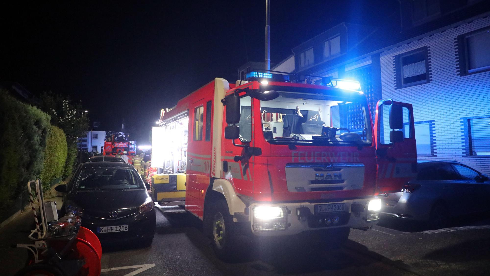 Ein Feuerwehrfahrzeug steht mit Blaulicht in einer Wohnstraße in Bergisch Gladbach-Lustheide.