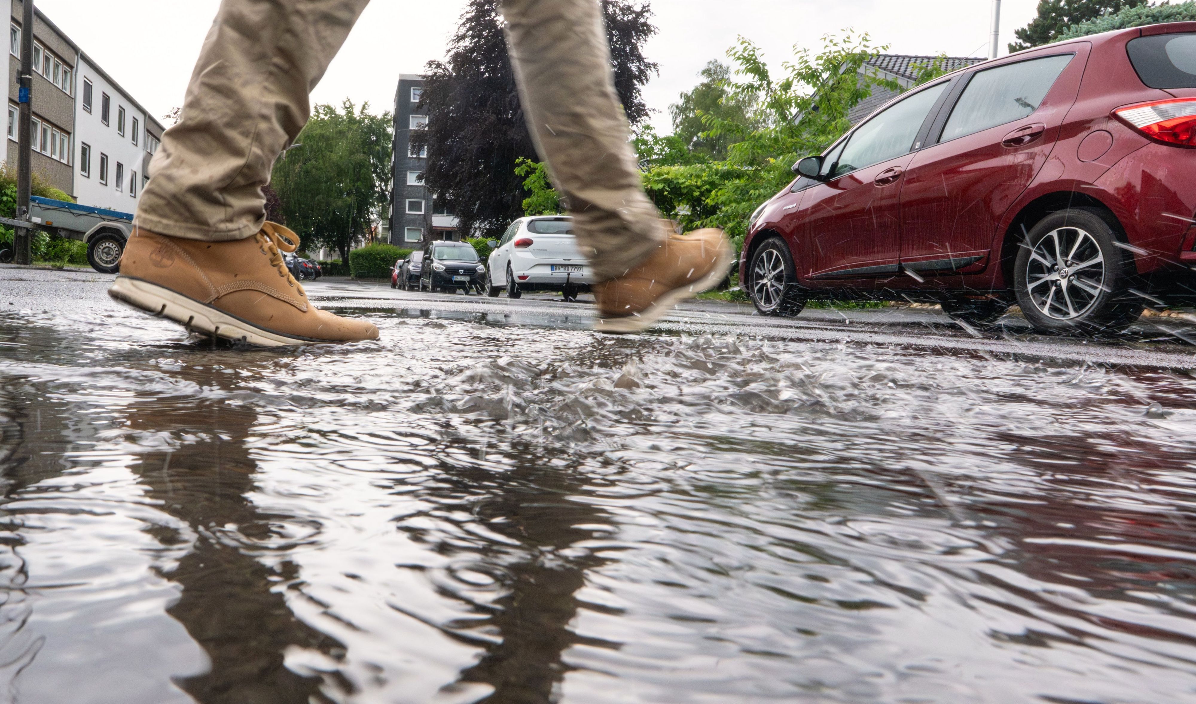 Ein Mann geht nach Regenschauern durch eine Pfütze. Der Sonntag begann in Nordrhein-Westfalen mit Regen und Gewittern.