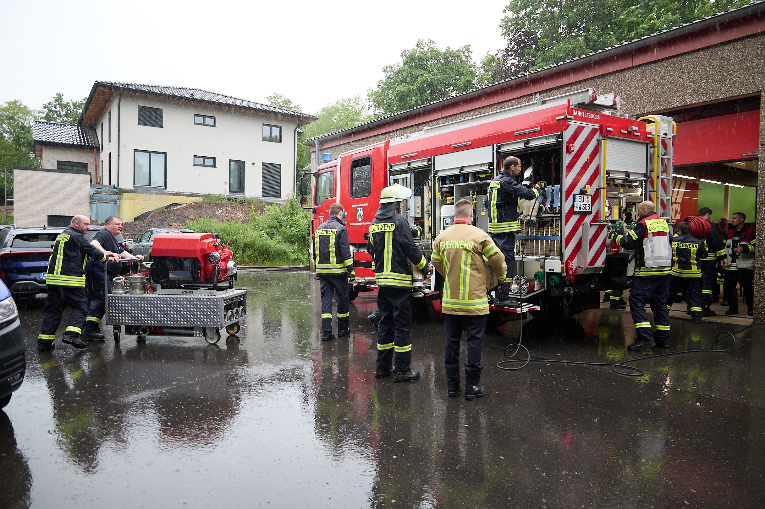 Das Bild zeigt Feuerwehrleute, wie sie ihre Ausrüstung wieder ins Fahrzeug packen.