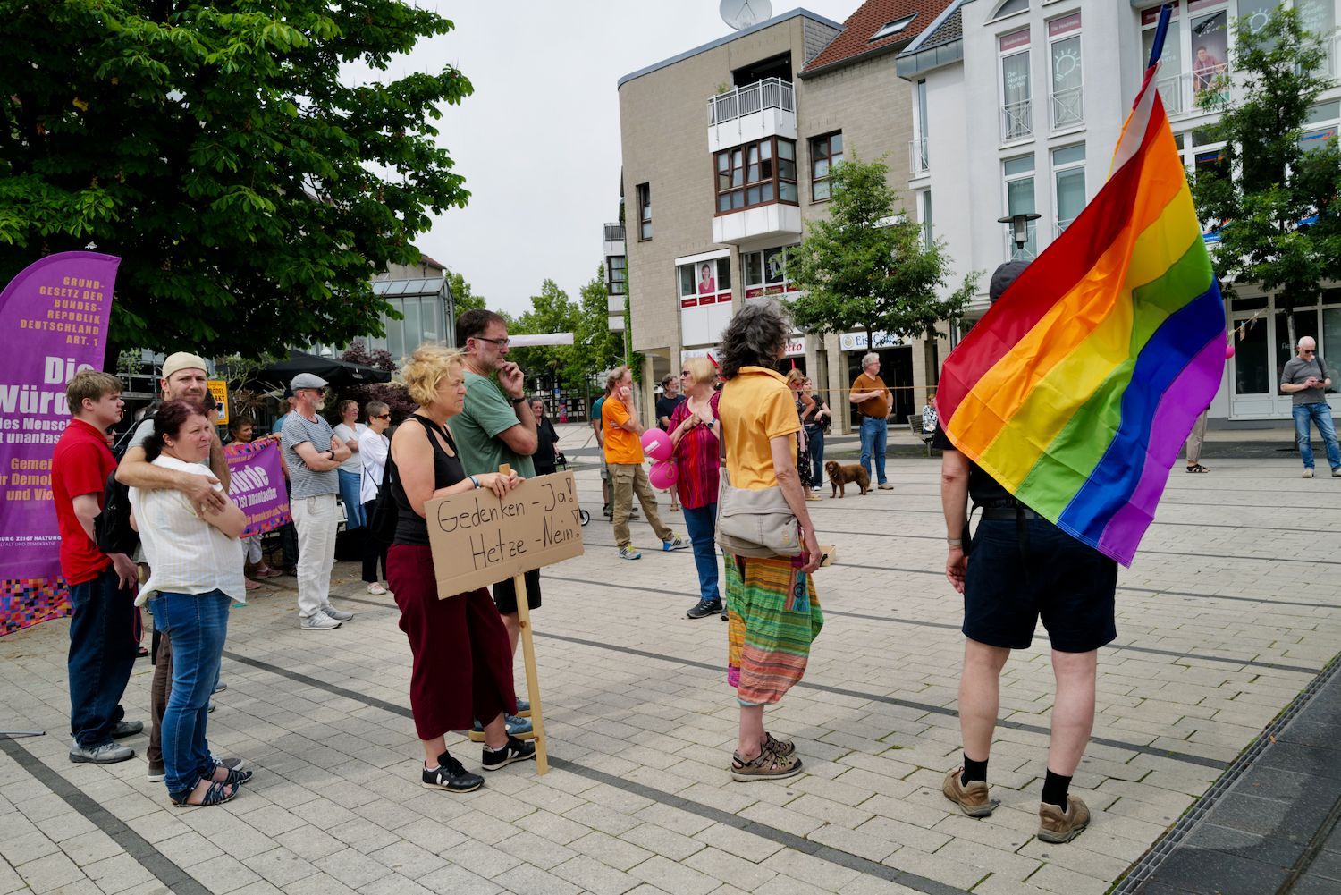 Eine Gruppe von Demonstranten mit Schildern und einer Regenbogenfahne.