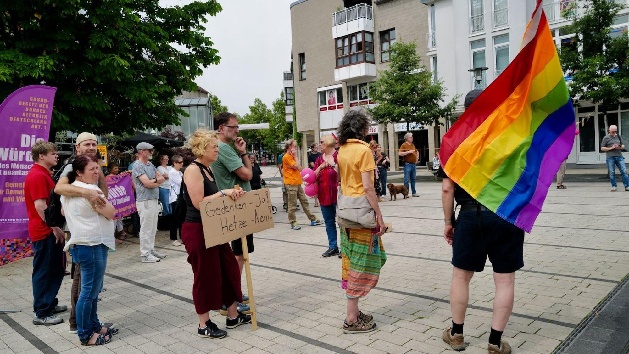 Eine Gruppe von Demonstranten mit Schildern und einer Regenbogenfahne.