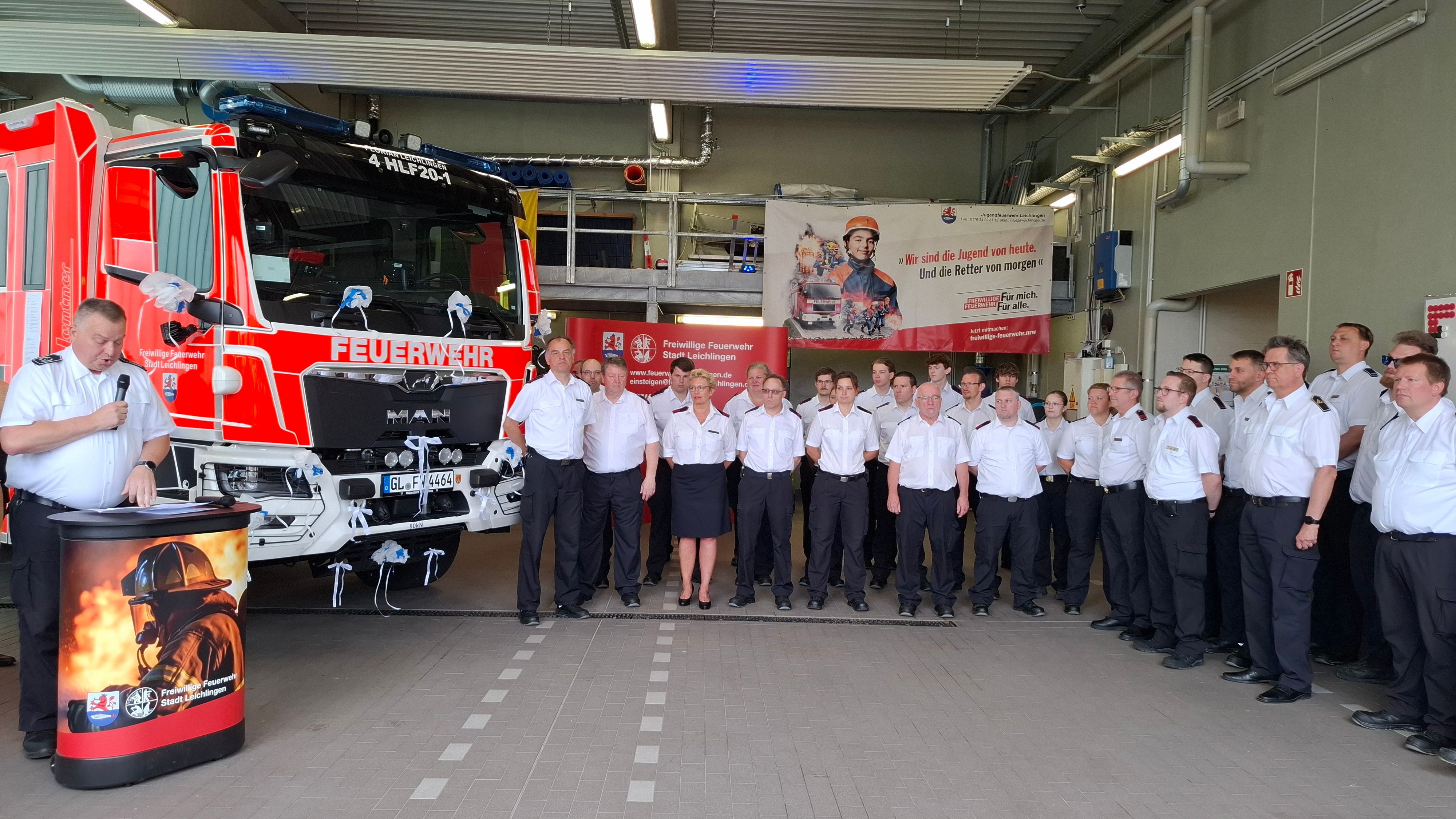 Feuerwehrleute stehen in einer Halle vor einem neuen Fahrzeug.